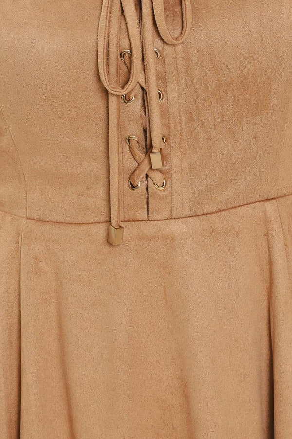 A woman modeling a sleeveless camel suede dress with a square neckline, front tie detail, and a flared skirt | Flying Tomato