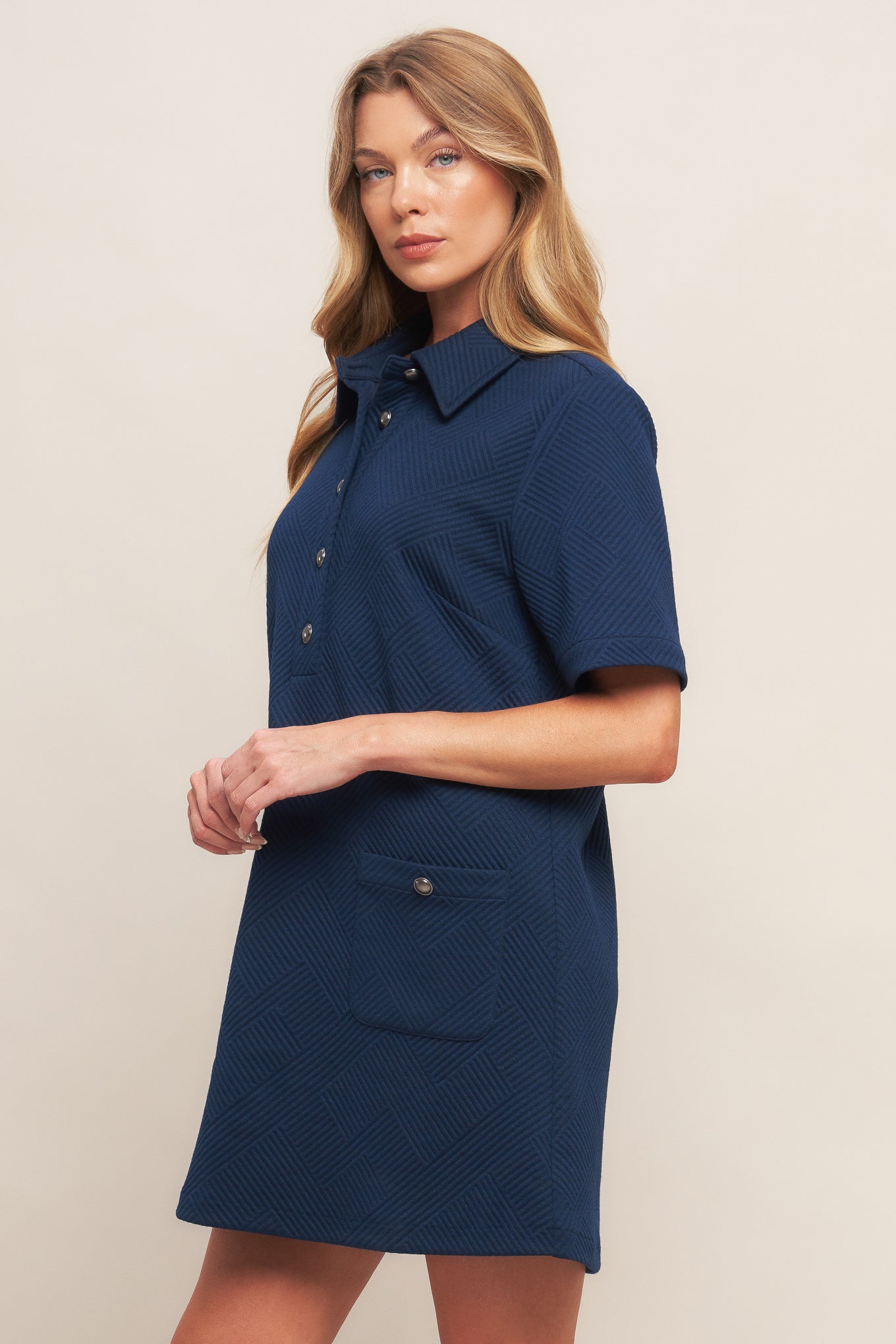 A textured knit mini dress featuring collar, front button down and short sleeve