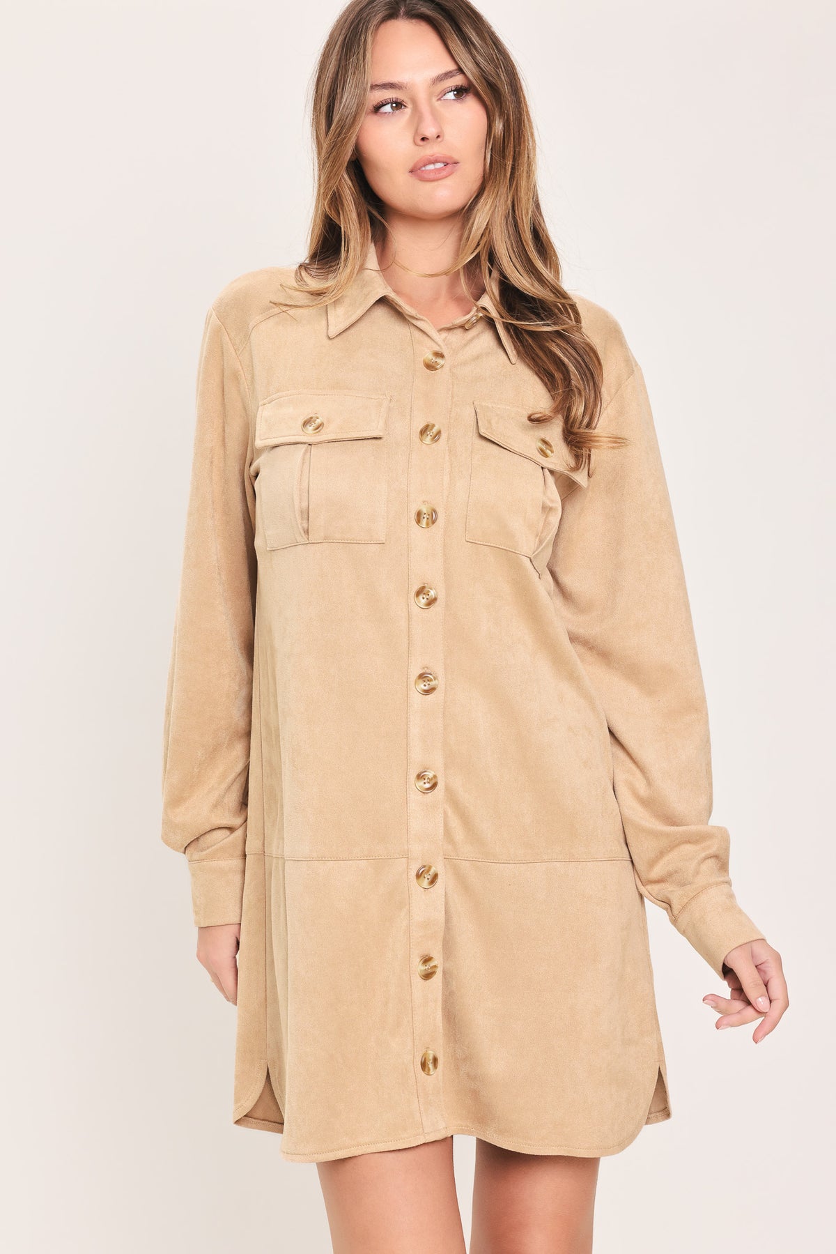 Woman wearing a long sleeve beige suede mini dress with buttons along the front, collar, and self tie matching belt | Flying Tomato