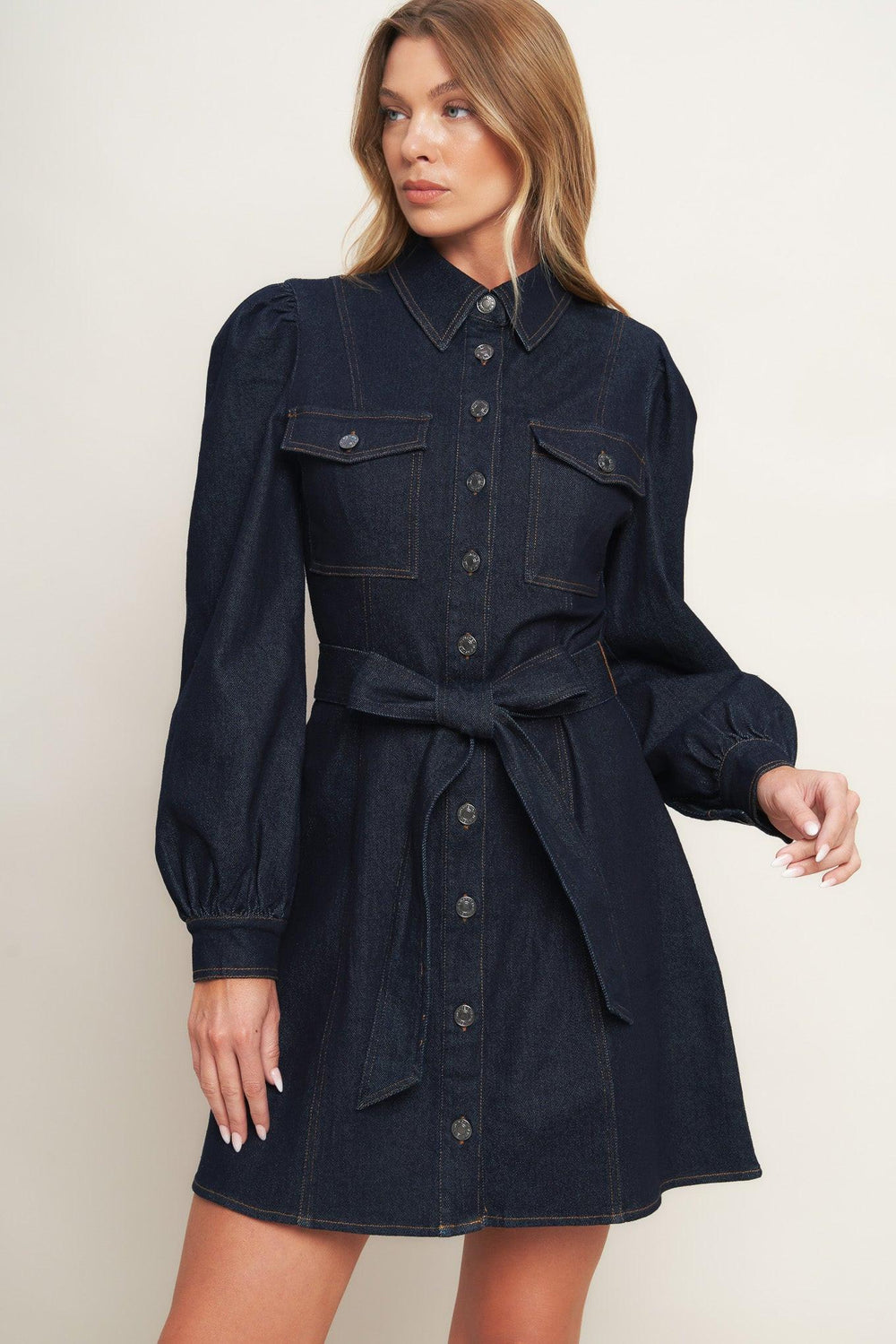 A denim mini dress featuring collar, long sleeve, front pocket, button down closure and self sash tie
