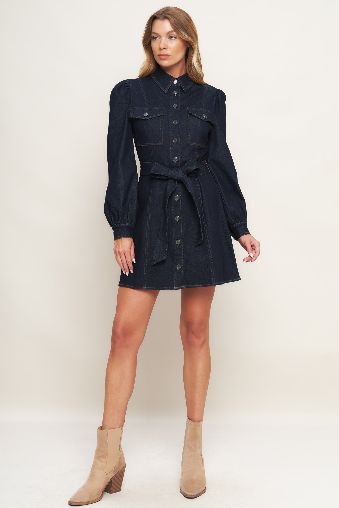A denim mini dress featuring collar, long sleeve, front pocket, button down closure and self sash tie