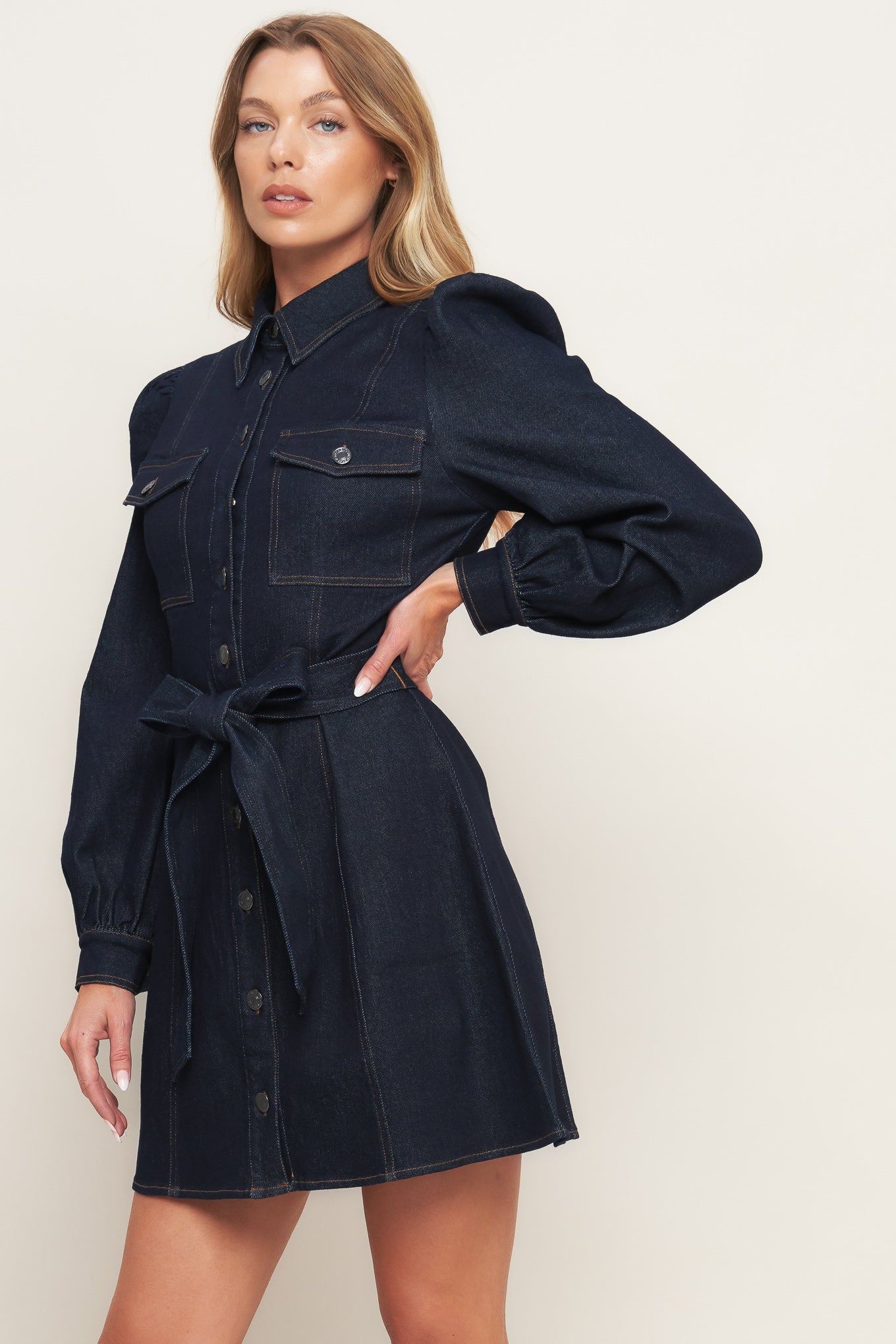 A denim mini dress featuring collar, long sleeve, front pocket, button down closure and self sash tie