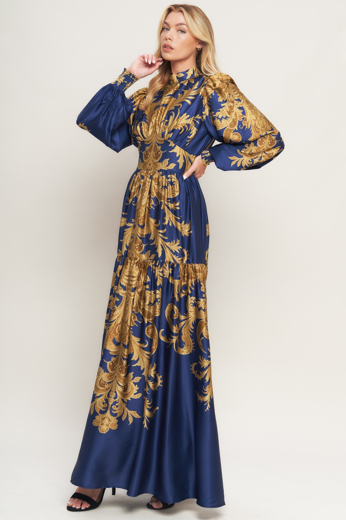 A printed woven maxi dress featuring mock neckline, blouson sleeve with smocked cuff, waist yoke, tiered skirt, smocked back waist band and back neck button closure