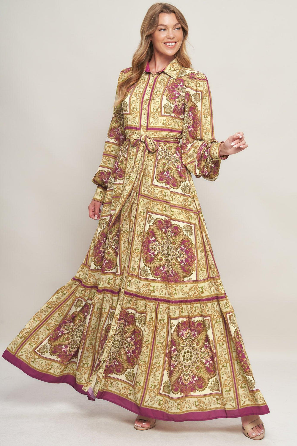 A printed woven maxi dress featuring collar, long sleeve with cuff, front button down, self sash tie and ruffled hemline