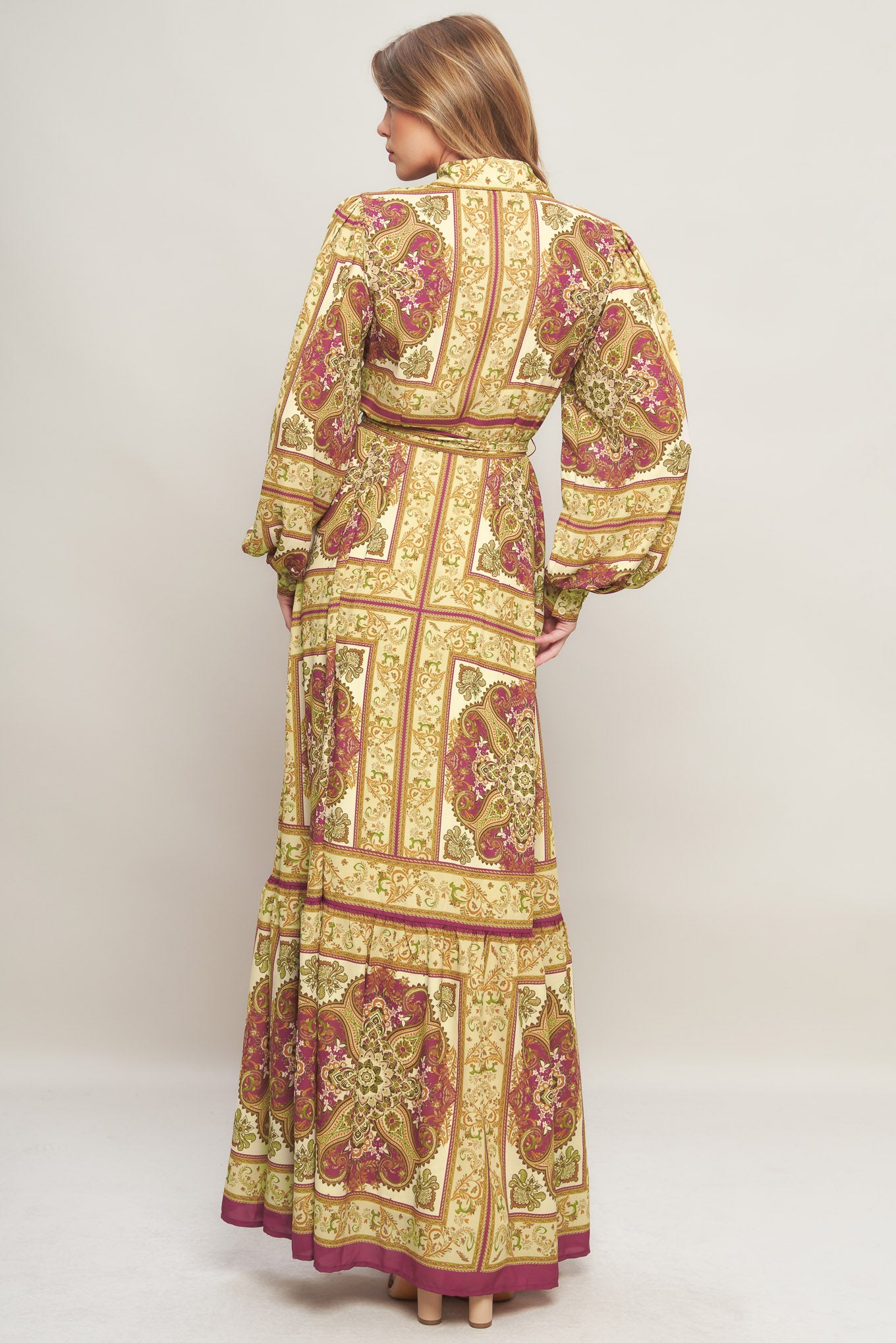 A printed woven maxi dress featuring collar, long sleeve with cuff, front button down, self sash tie and ruffled hemline