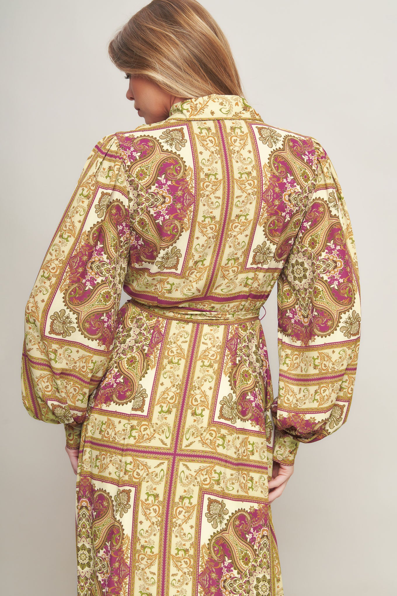 A printed woven maxi dress featuring collar, long sleeve with cuff, front button down, self sash tie and ruffled hemline