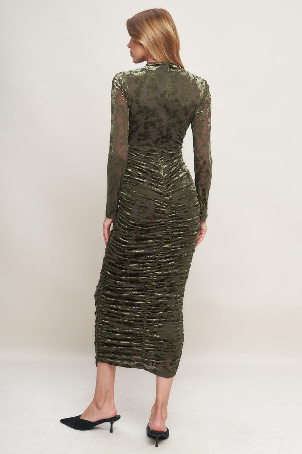A burnout velvet midi dress featuring tubular neckline, long sleeve, side shirring and back zipper closure