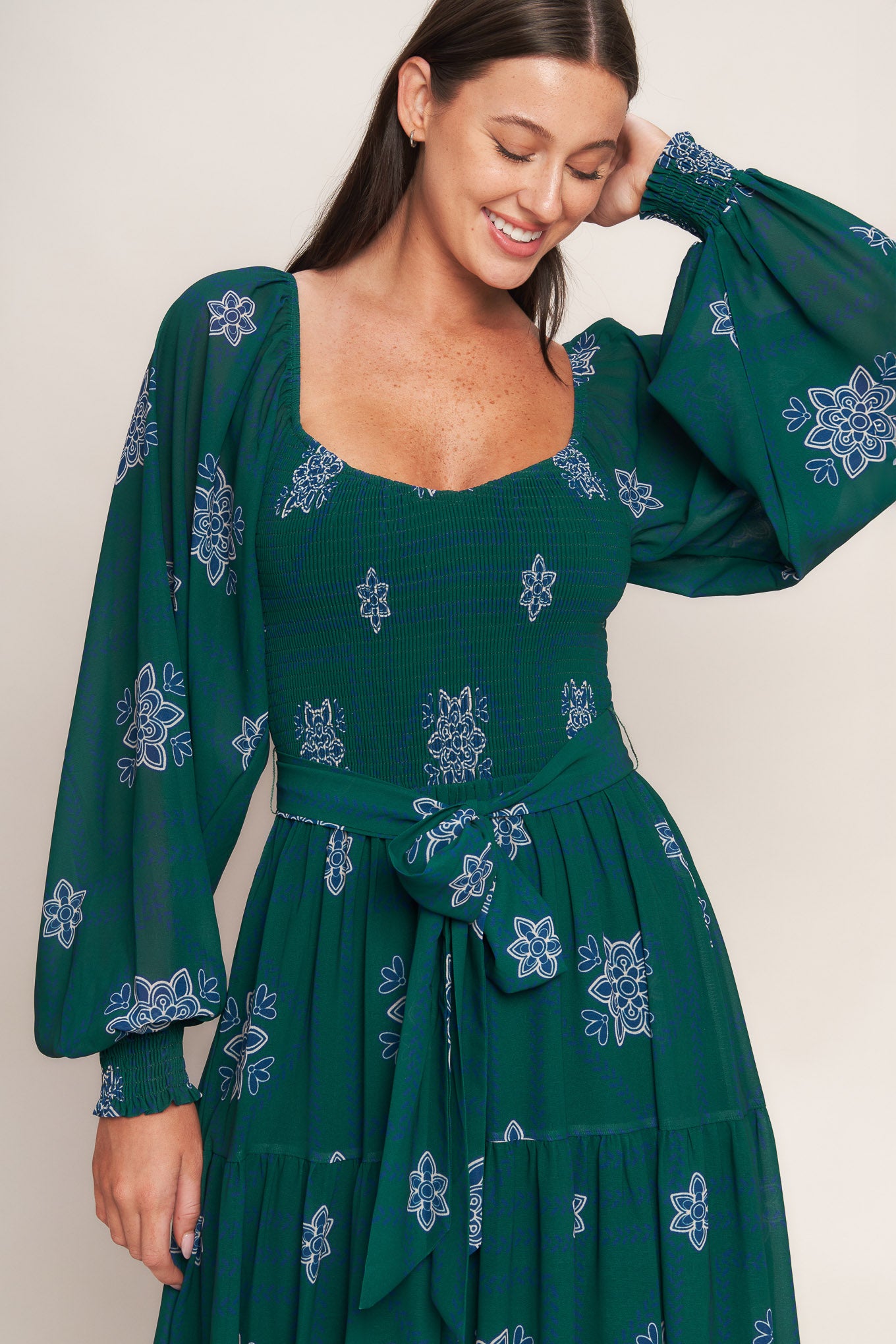 A printed woven maxi dress featuring sweetheart neckline, long sleeve with ruffled cuff, smocked bodice, tiered skirt and self sash tie