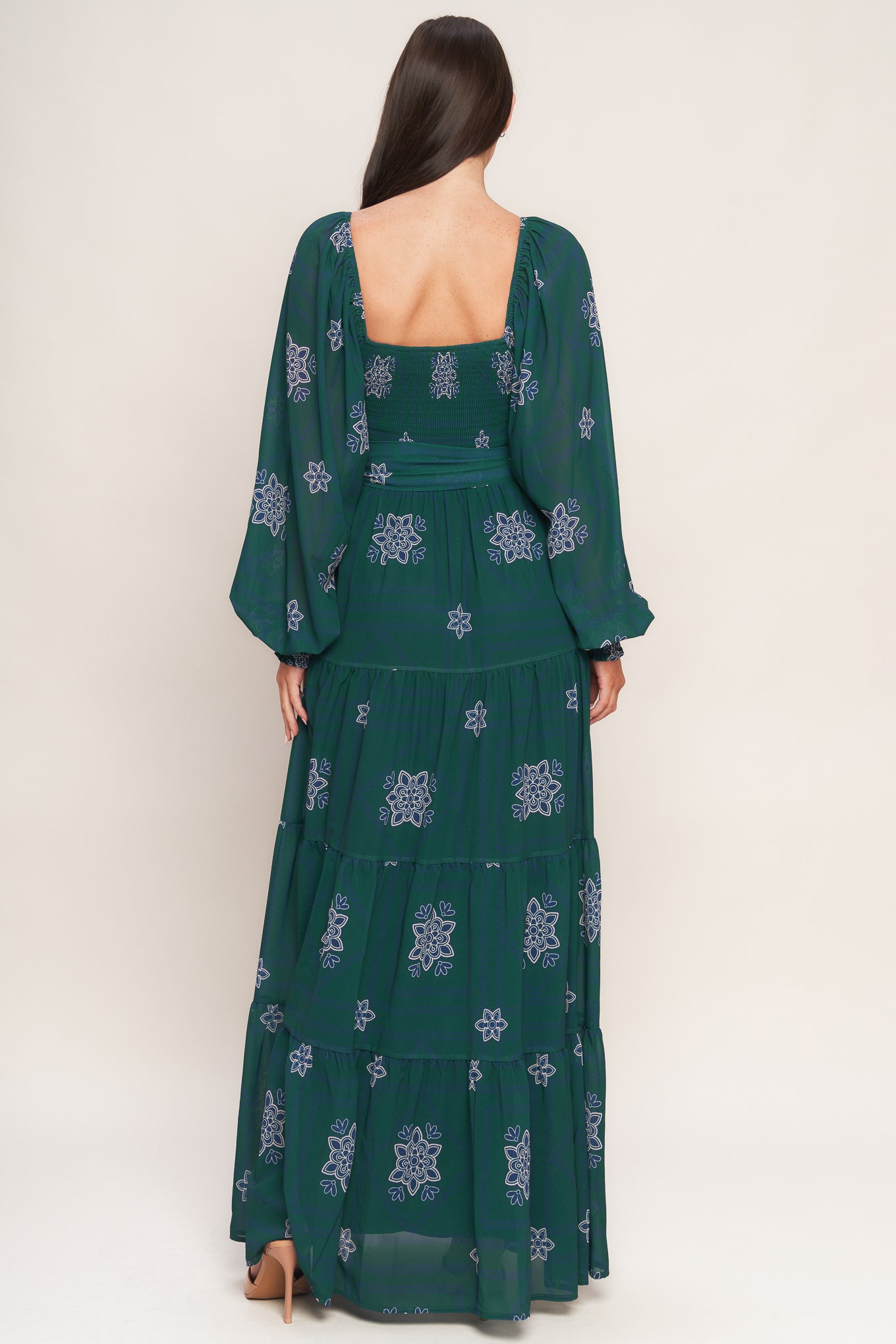 A printed woven maxi dress featuring sweetheart neckline, long sleeve with ruffled cuff, smocked bodice, tiered skirt and self sash tie