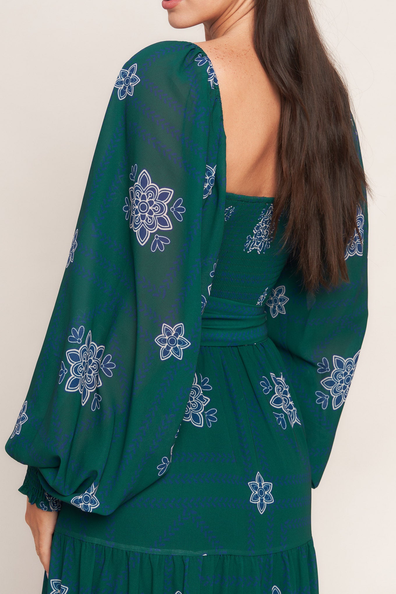 A printed woven maxi dress featuring sweetheart neckline, long sleeve with ruffled cuff, smocked bodice, tiered skirt and self sash tie