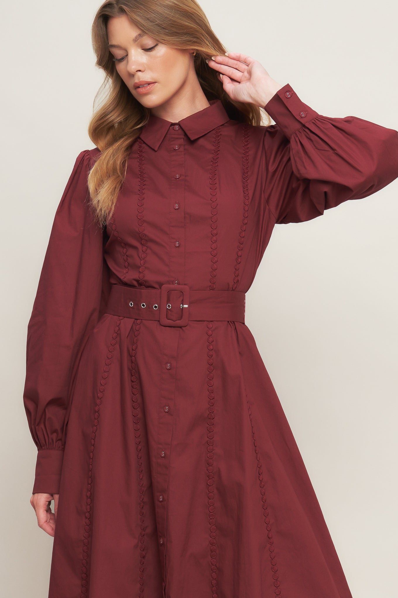 A solid woven midi dress featuring collar, button down, lace trim detail, long sleeve, self belt and full skirt