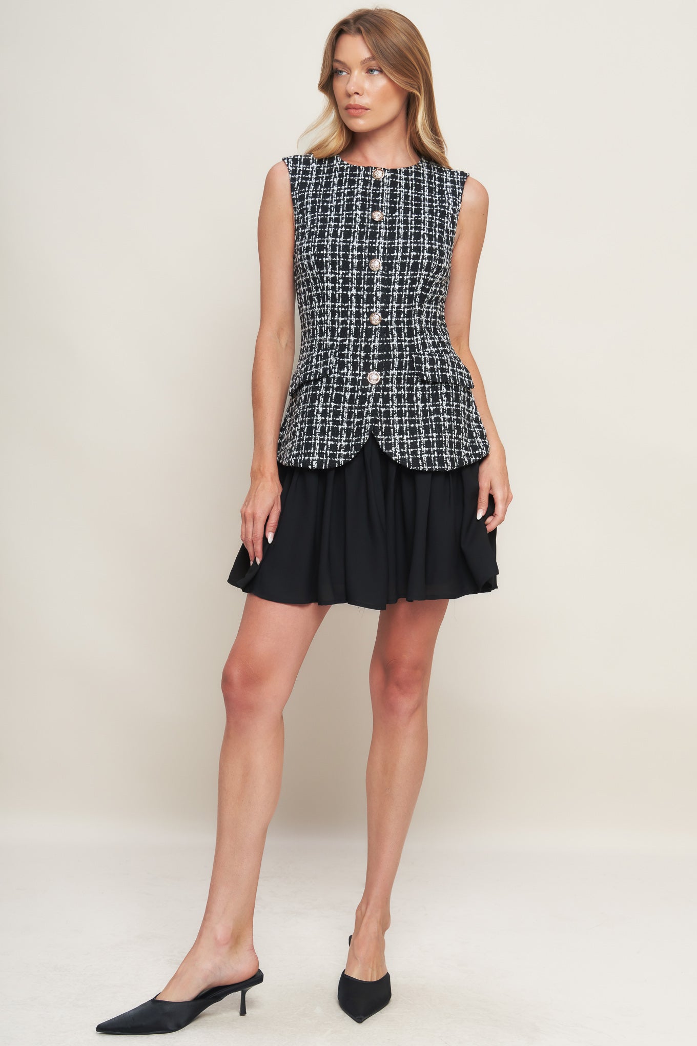 A tweed and solid woven mini dress featuring round neckline, sleeveless, front button down and flowy solid skirt