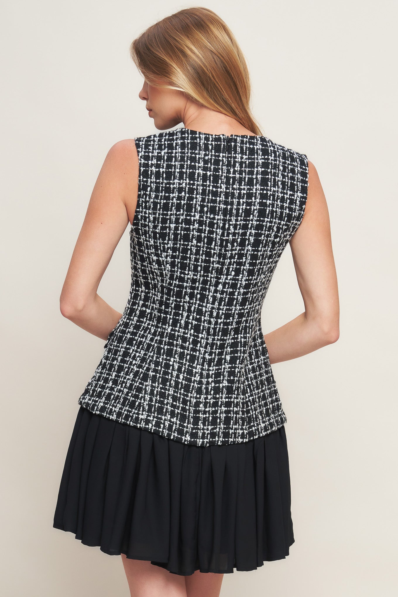 A tweed and solid woven mini dress featuring round neckline, sleeveless, front button down and flowy solid skirt