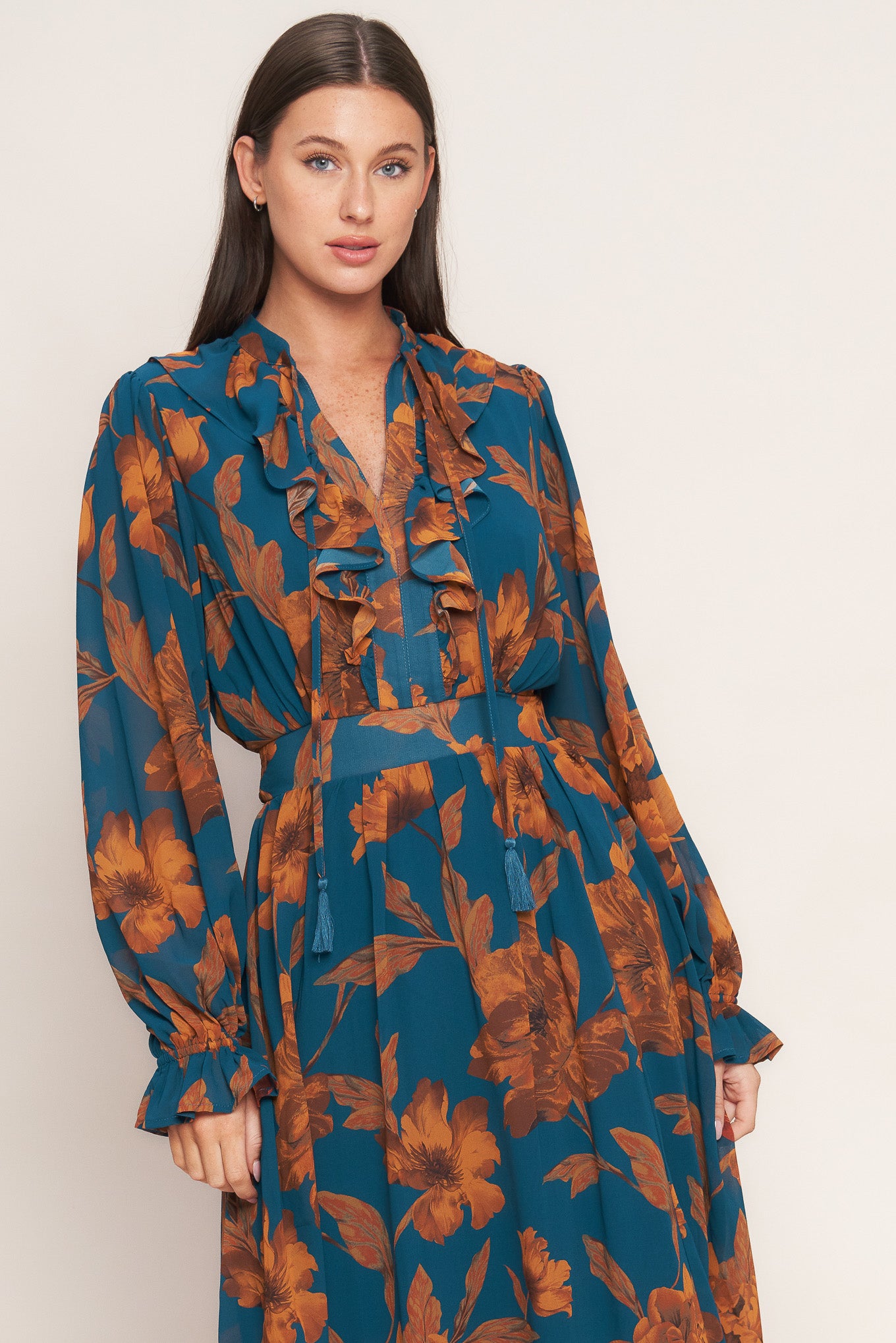 A printed woven midi dress featuring front tie/tassel with ruffles, long sleeve with ruffled cuff and elasticized waist