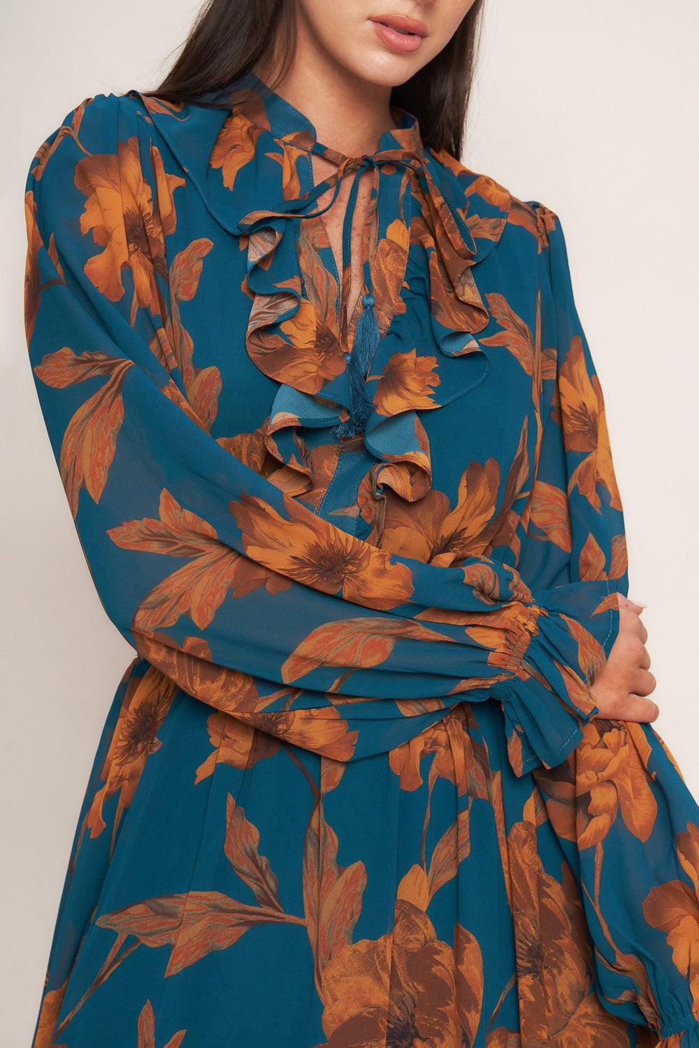 A printed woven midi dress featuring front tie/tassel with ruffles, long sleeve with ruffled cuff and elasticized waist