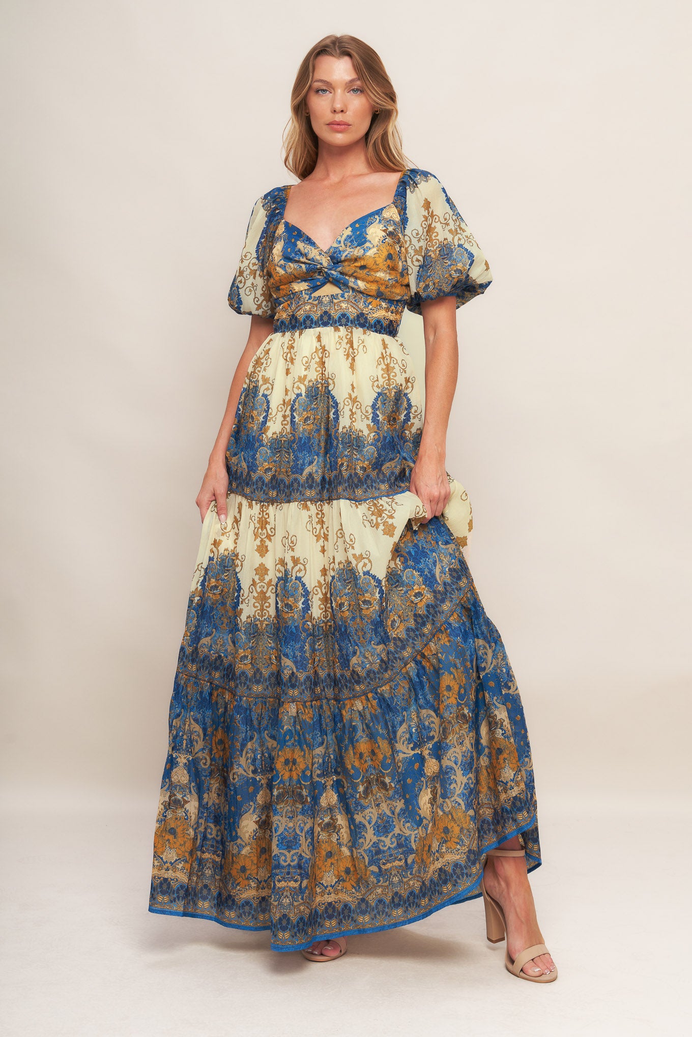 A printed woven maxi dress featuring sweetheart neckline with twisted front and cut out, short puff sleeve, tiered skirt and smocked back bodice