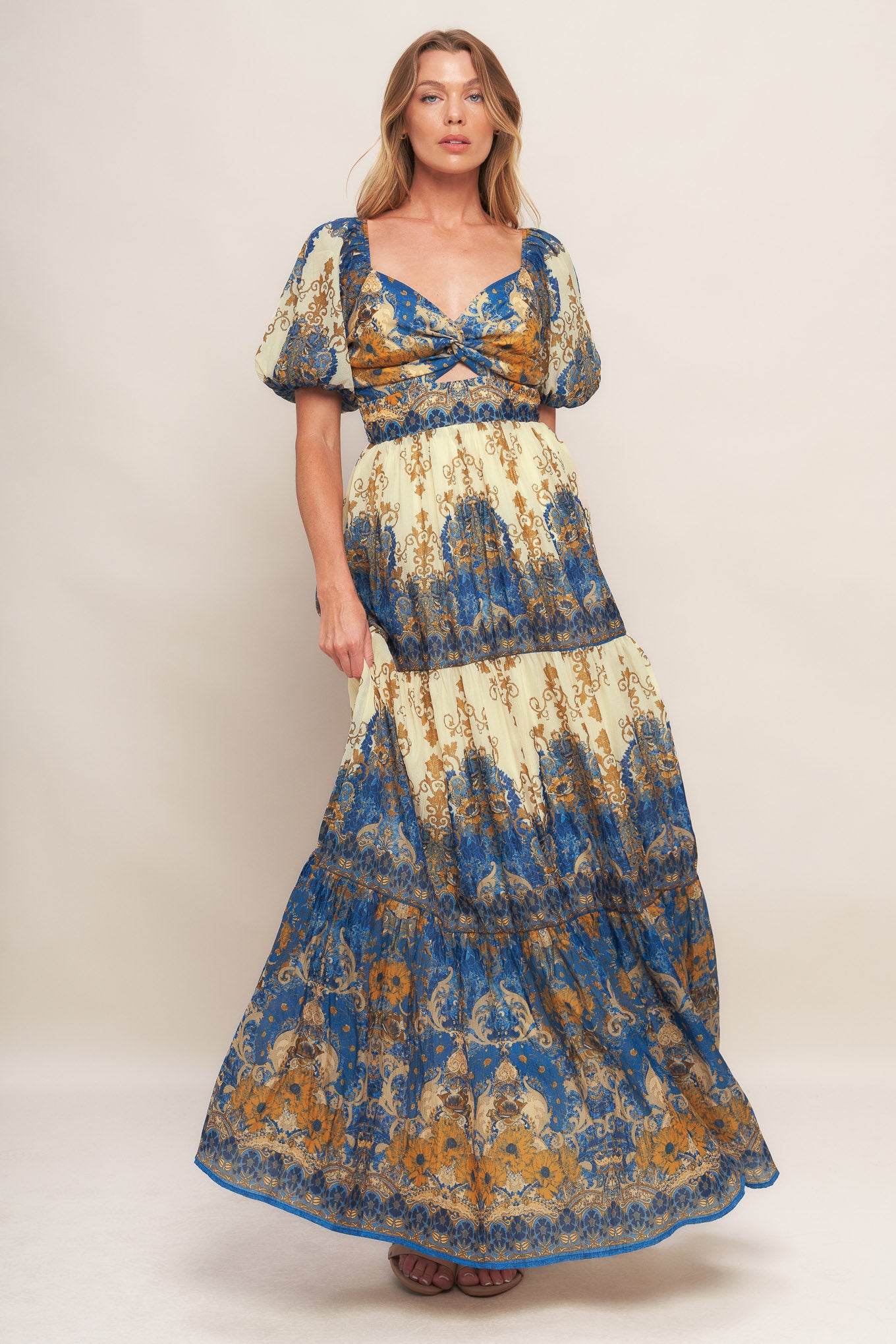 A printed woven maxi dress featuring sweetheart neckline with twisted front and cut out, short puff sleeve, tiered skirt and smocked back bodice