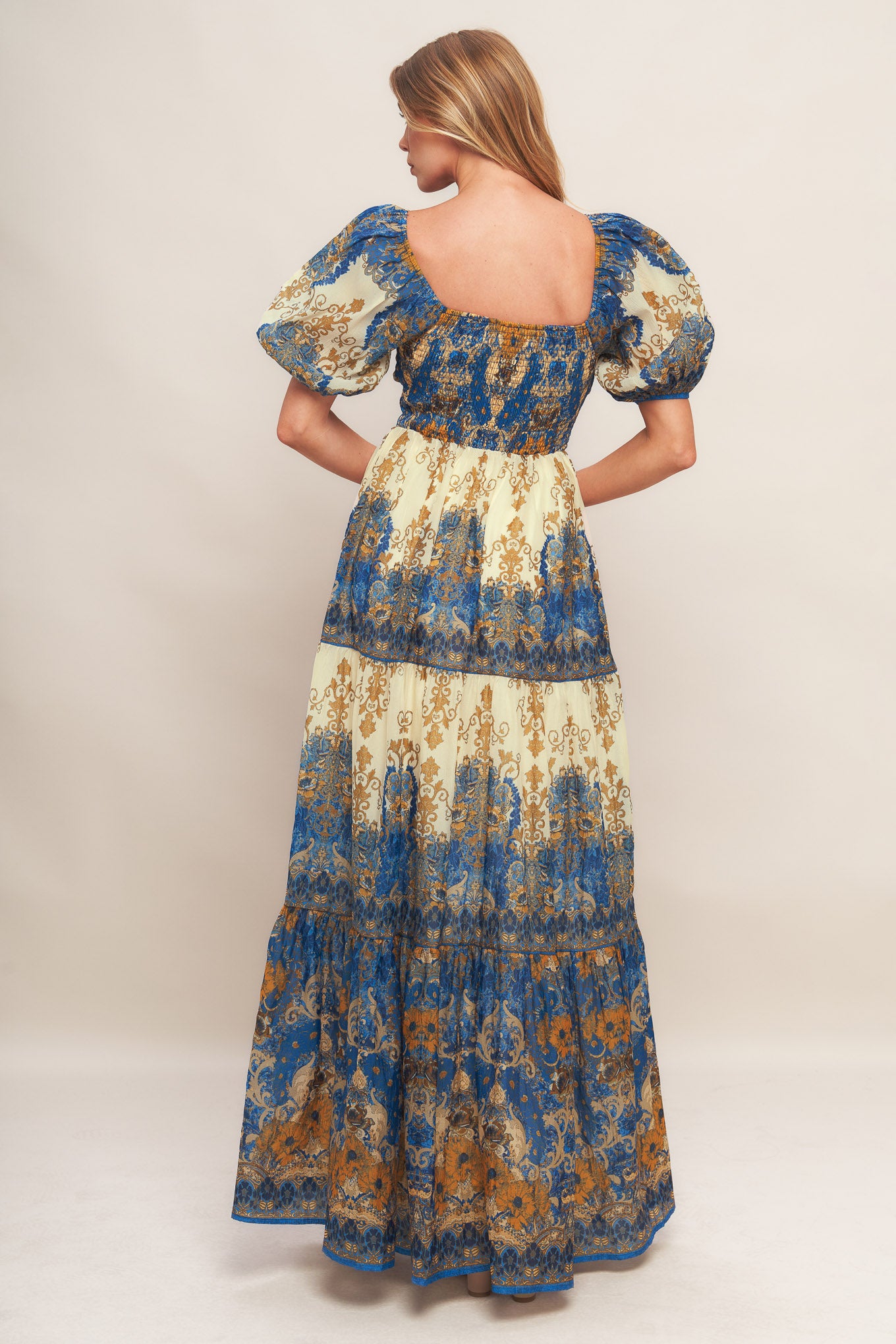 A printed woven maxi dress featuring sweetheart neckline with twisted front and cut out, short puff sleeve, tiered skirt and smocked back bodice