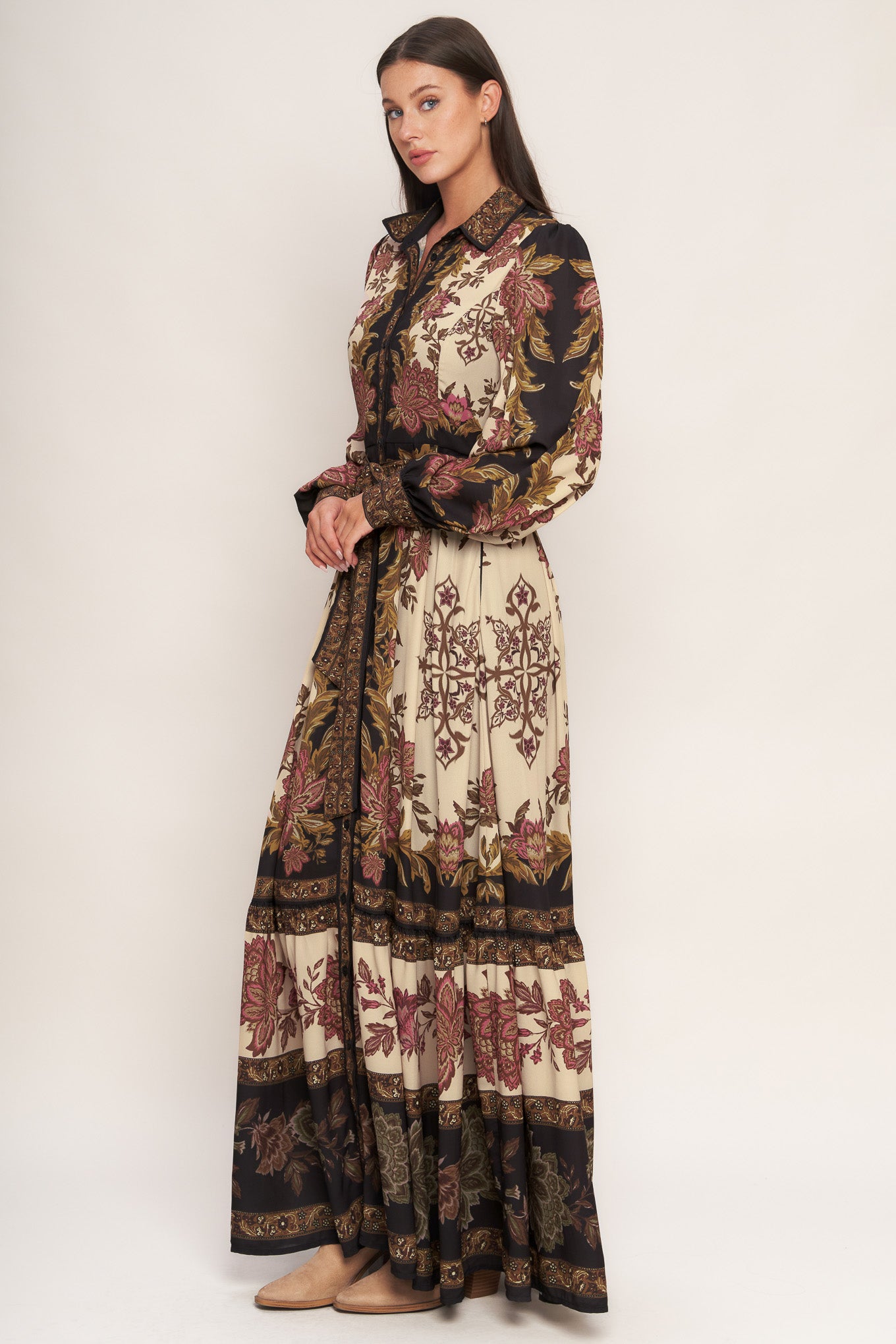 A printed woven maxi dress featuring collar, button down, long sleeve with cuff, self sash tie, and ruffled hemline