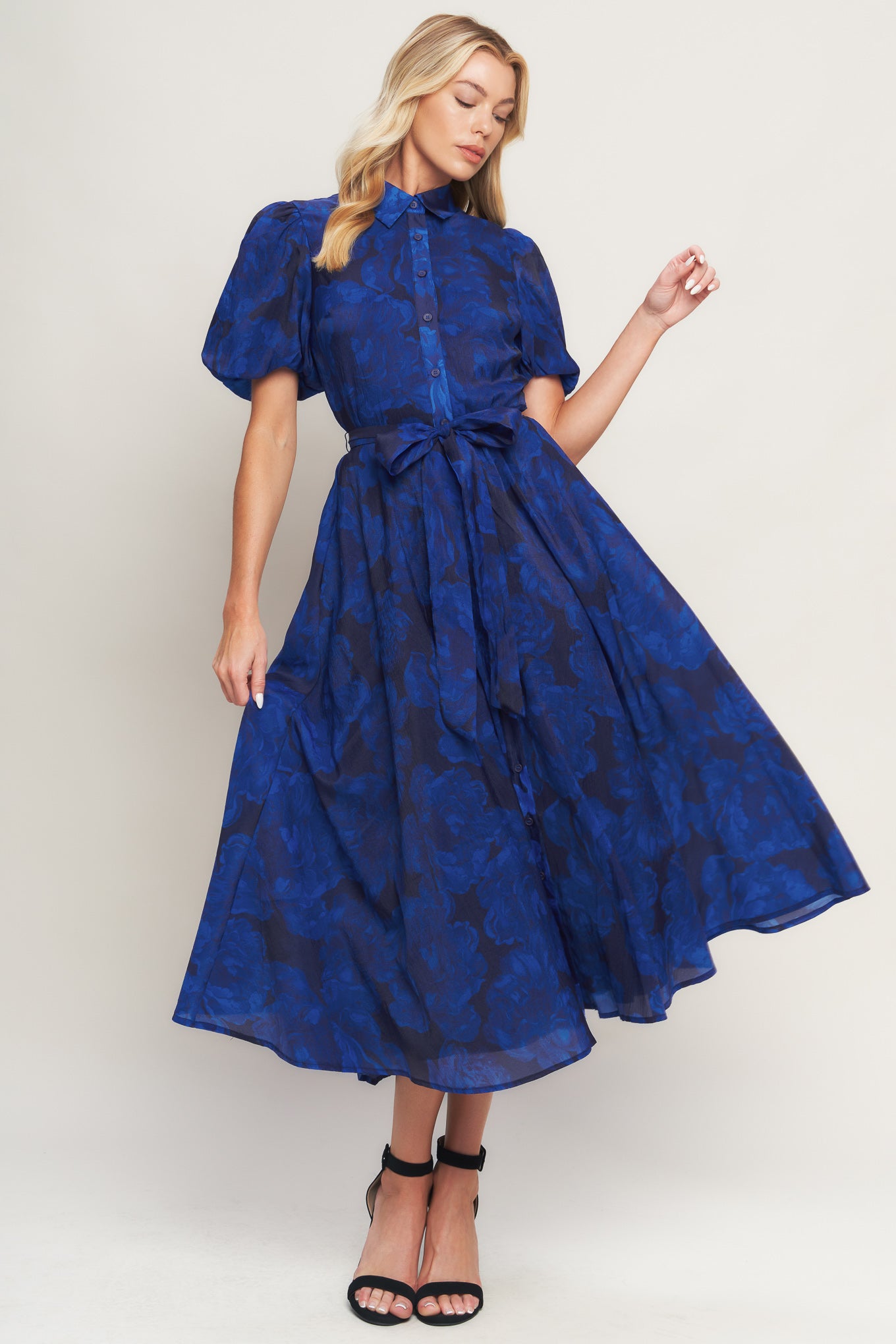 A printed woven midi dress featuring collar, front button down, short puff sleeve, self sash tie and full skirt