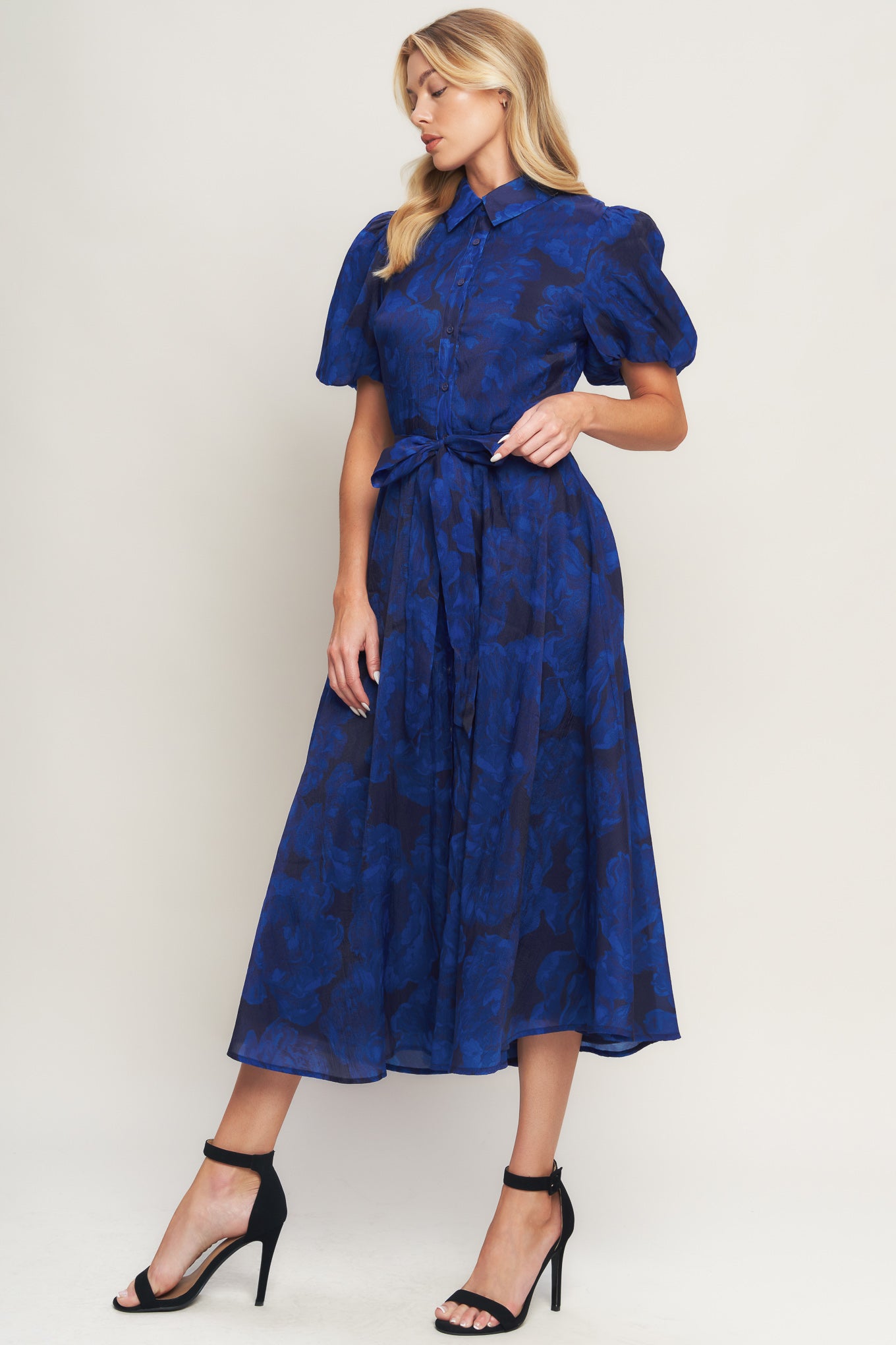 A printed woven midi dress featuring collar, front button down, short puff sleeve, self sash tie and full skirt