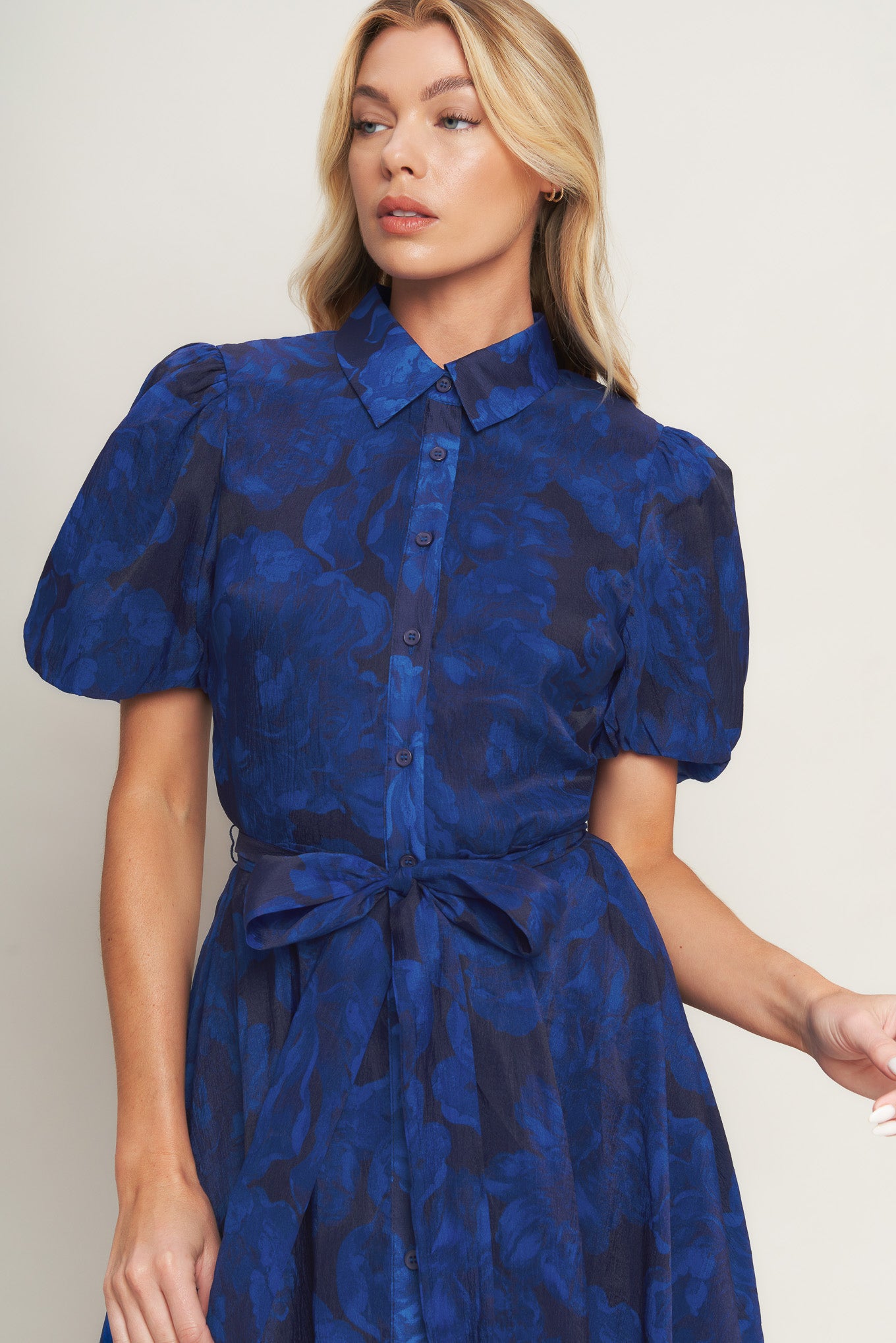A printed woven midi dress featuring collar, front button down, short puff sleeve, self sash tie and full skirt