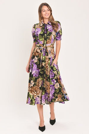 Woman wearing a black short sleeve, collared, button shirt dress with purple and gold floral pattern and a self tie waist belt | Flying Tomato