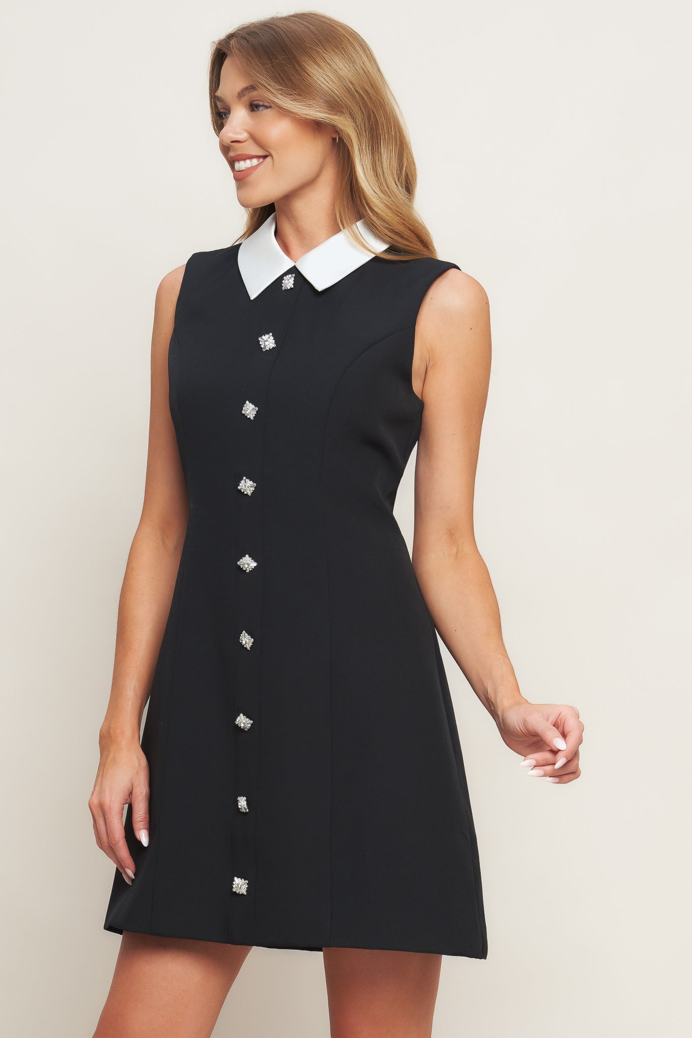 A solid woven mini dress featuring collar, sleeveless, front button detail and back zipper closure