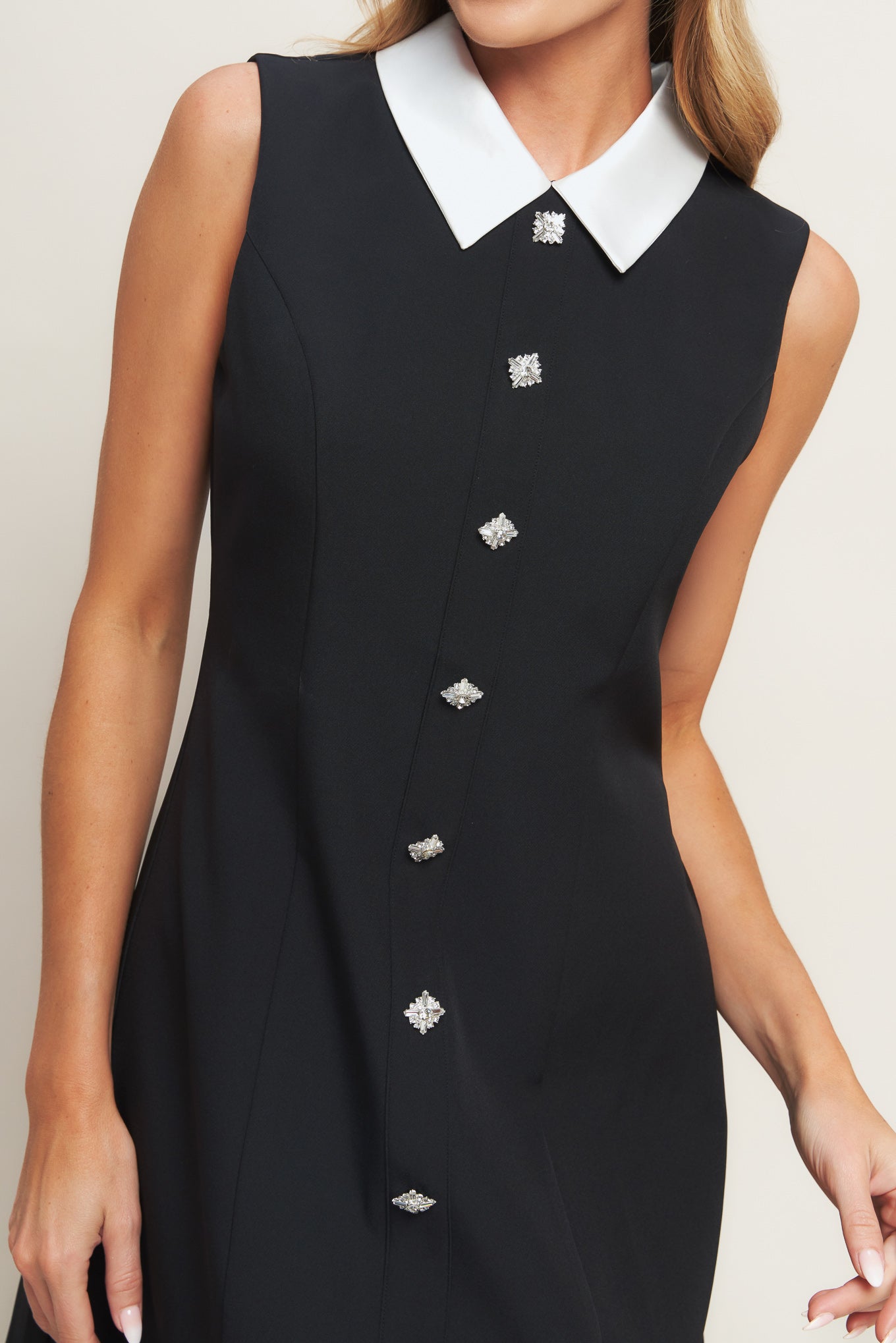 A solid woven mini dress featuring collar, sleeveless, front button detail and back zipper closure