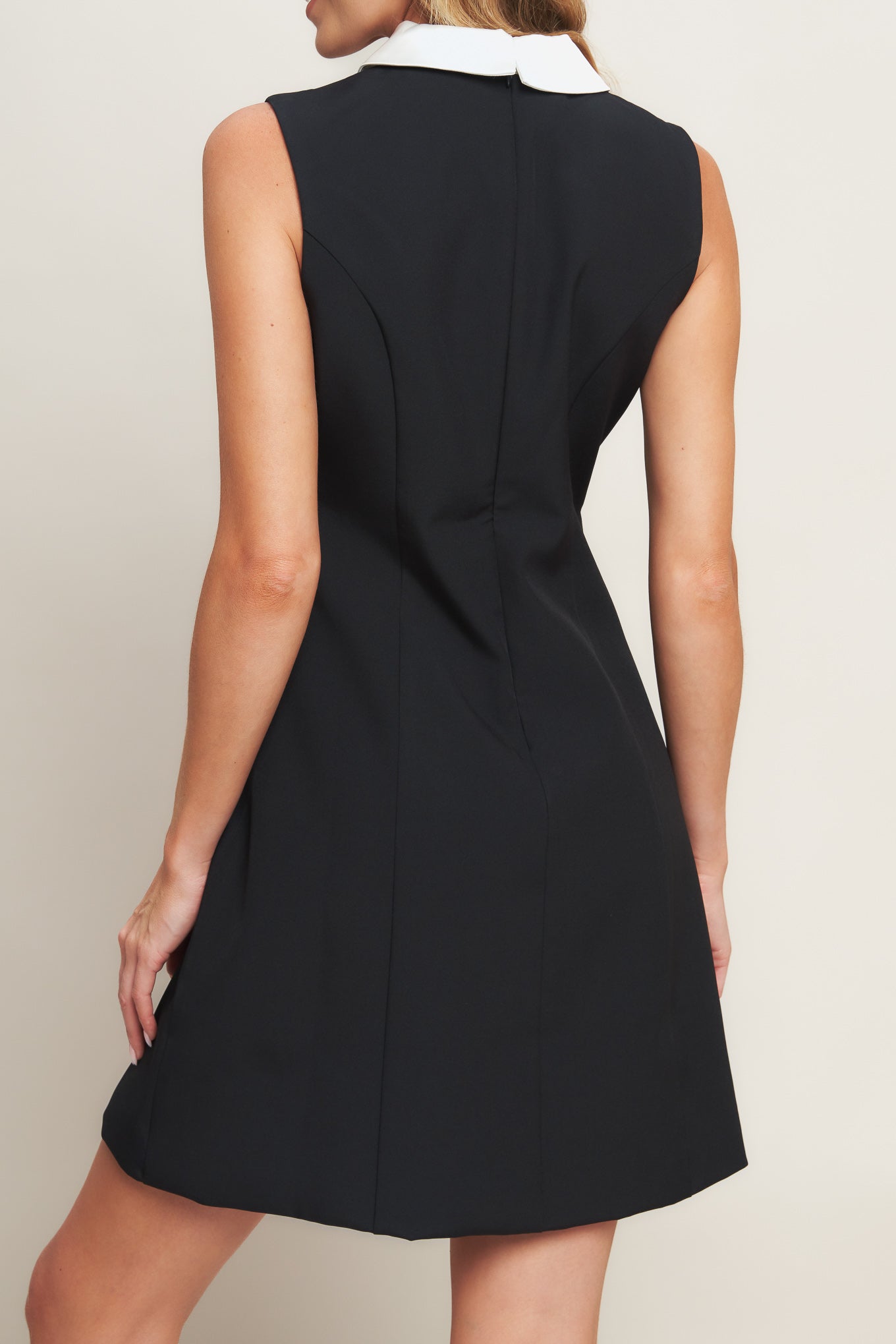 A solid woven mini dress featuring collar, sleeveless, front button detail and back zipper closure