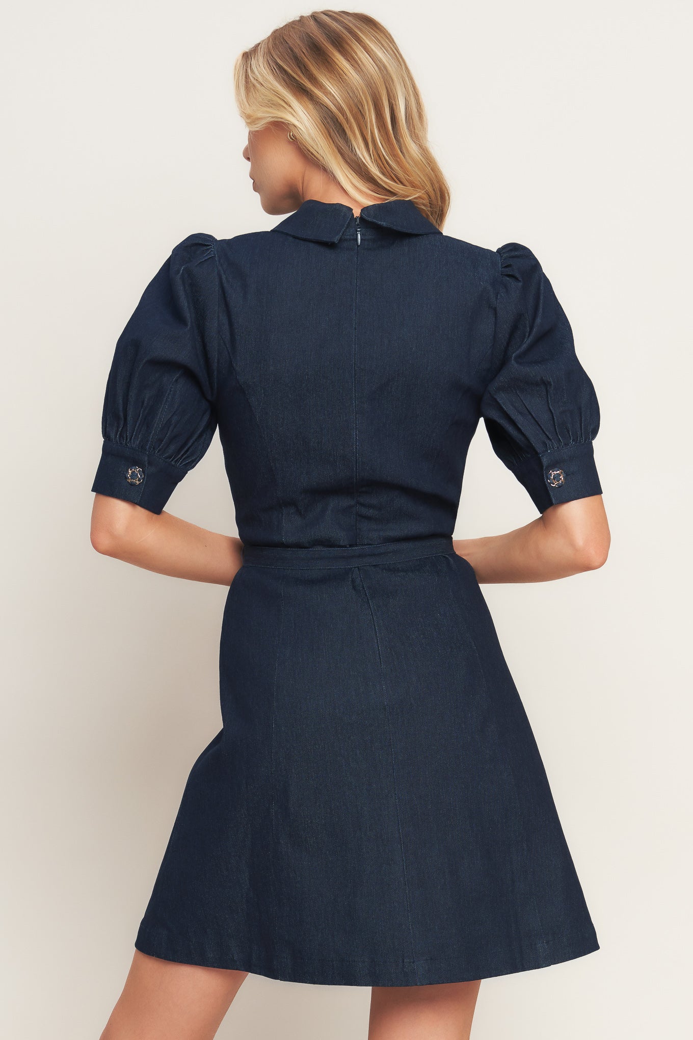 A denim mini dress featuring collar, 3/4 sleeve, front button down detail and back zipper closure