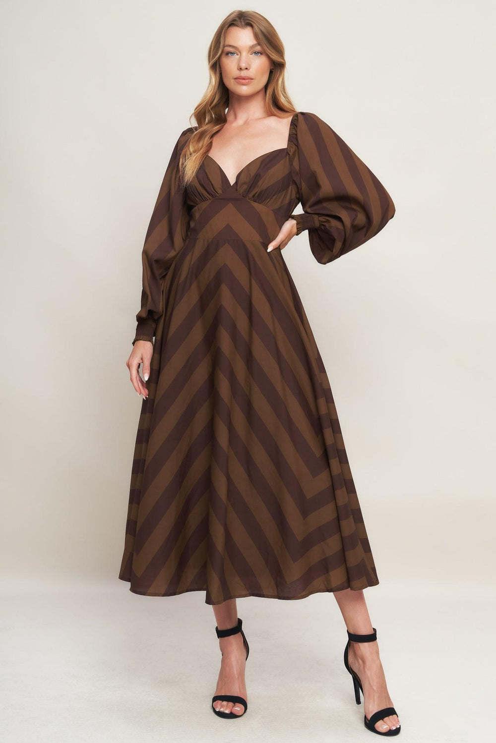 A printed woven midi dress featuring sweetheart neckline, long sleeve with smocked cuff, waist yoke, circle skirt and back zipper closure