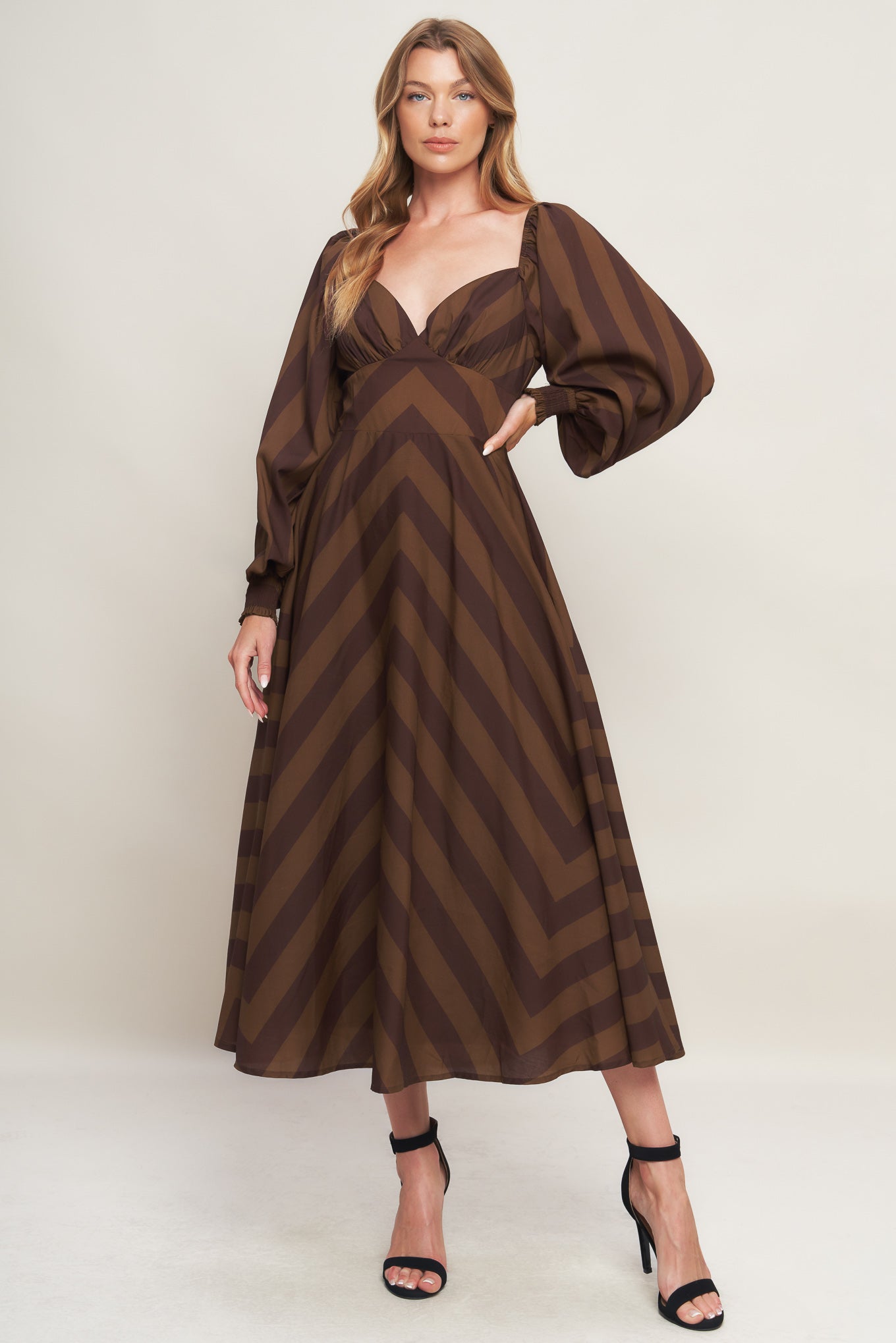 A printed woven midi dress featuring sweetheart neckline, long sleeve with smocked cuff, waist yoke, circle skirt and back zipper closure