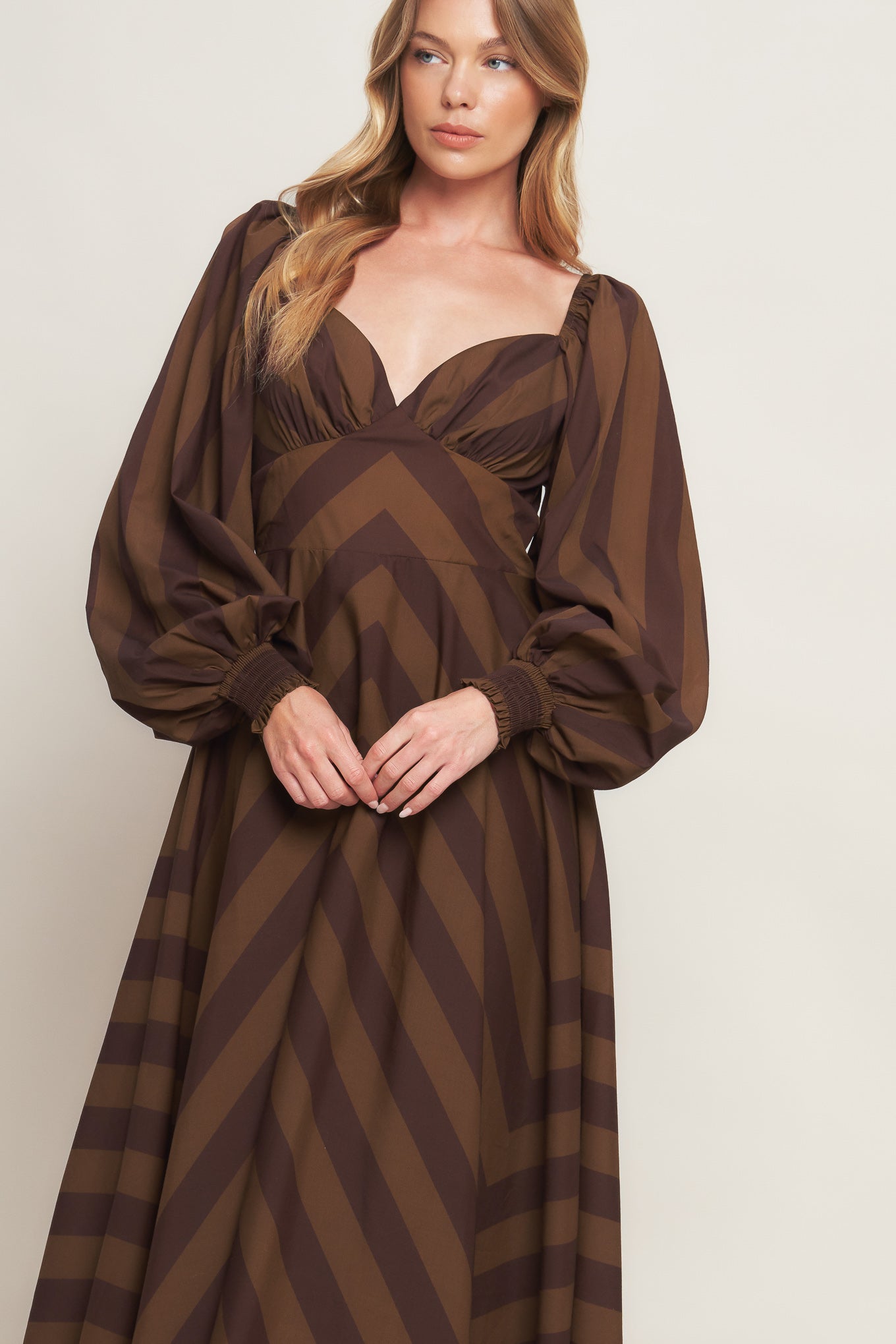 A printed woven midi dress featuring sweetheart neckline, long sleeve with smocked cuff, waist yoke, circle skirt and back zipper closure