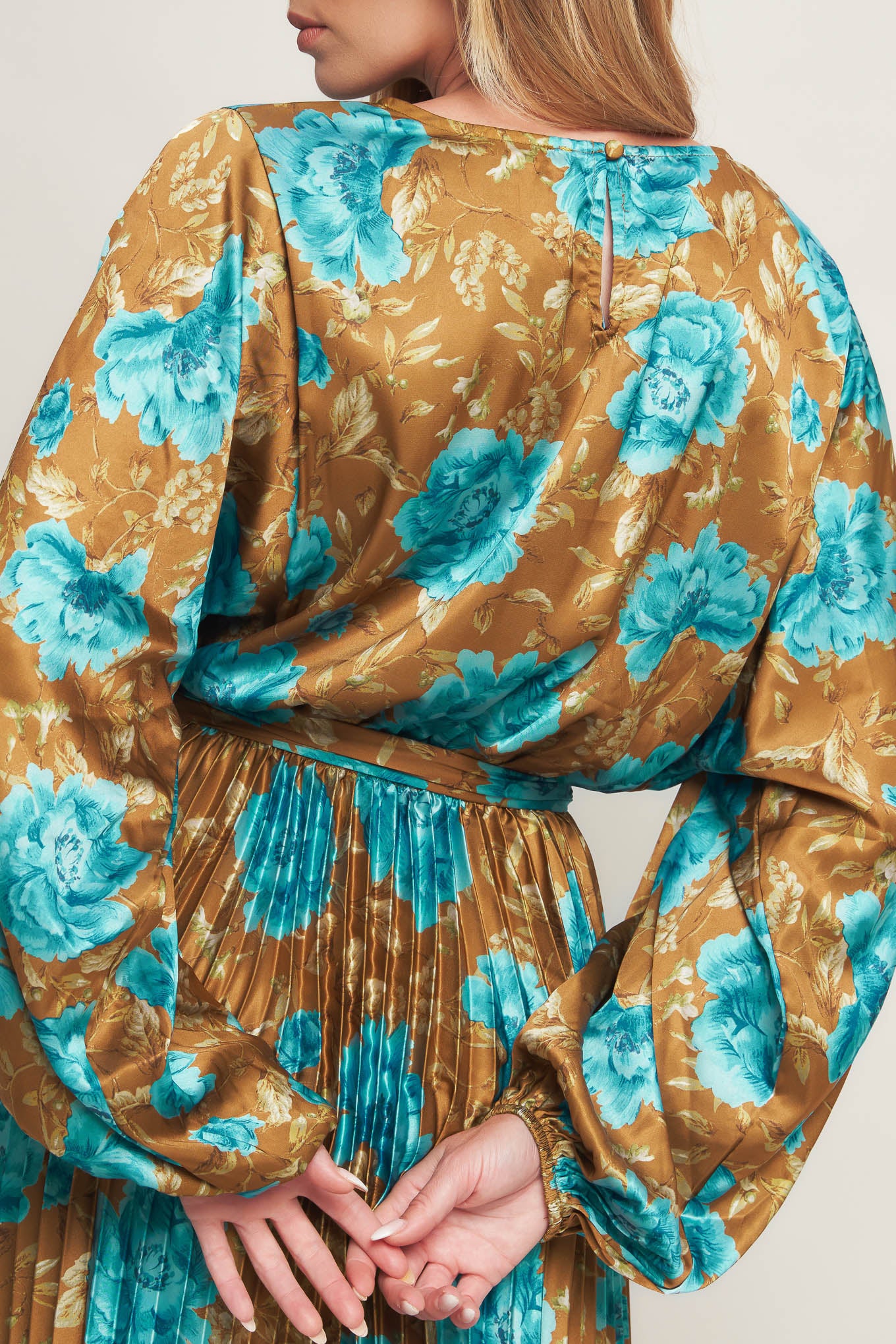 A printed woven satin maxi dress featuring round neckline, long sleeve, elasticized waist with pleated skirt and back button closure