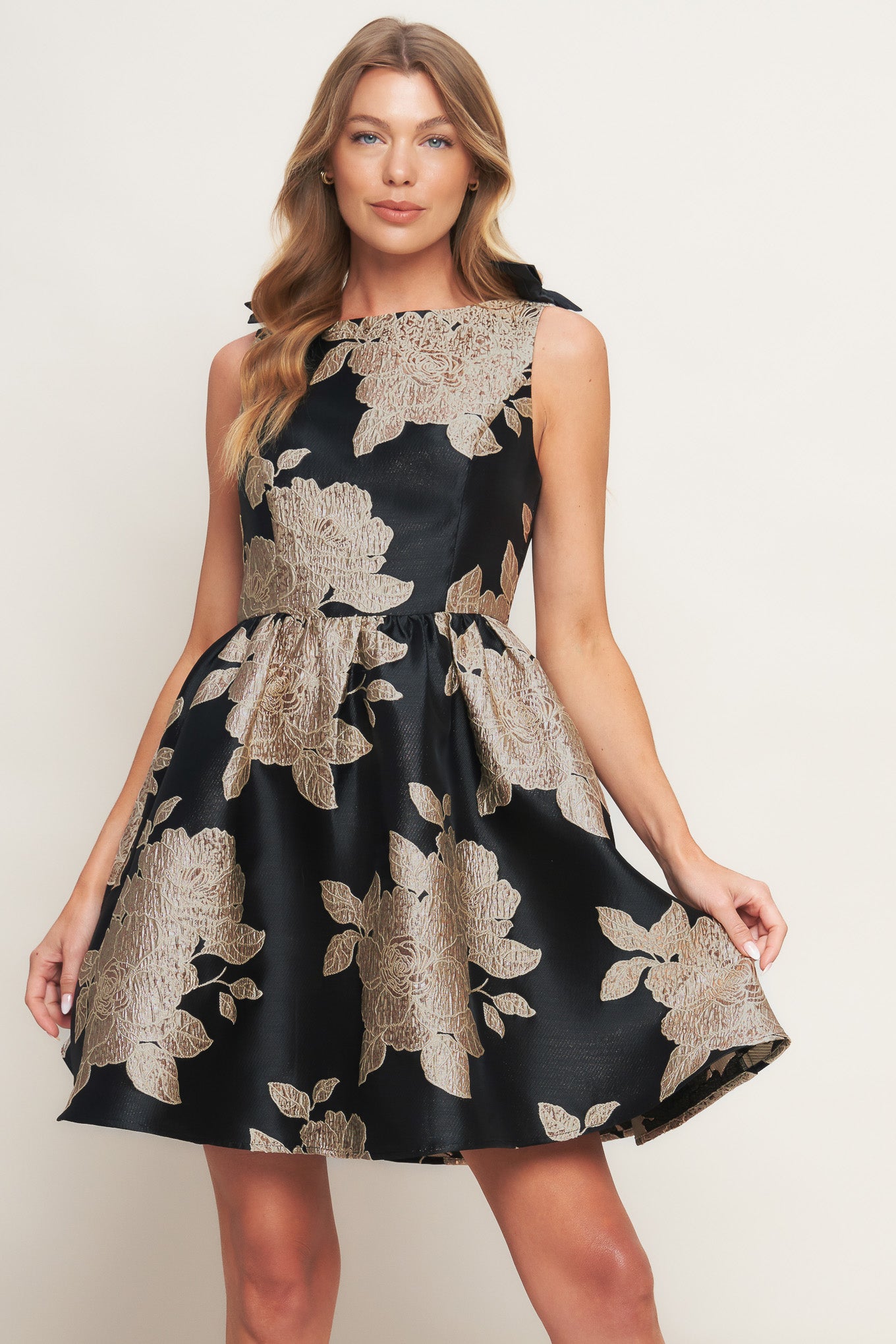 A textured woven mini dress featuring wide neckline, sleeveless, shoulder bow detail, full skirt and back zipper closure