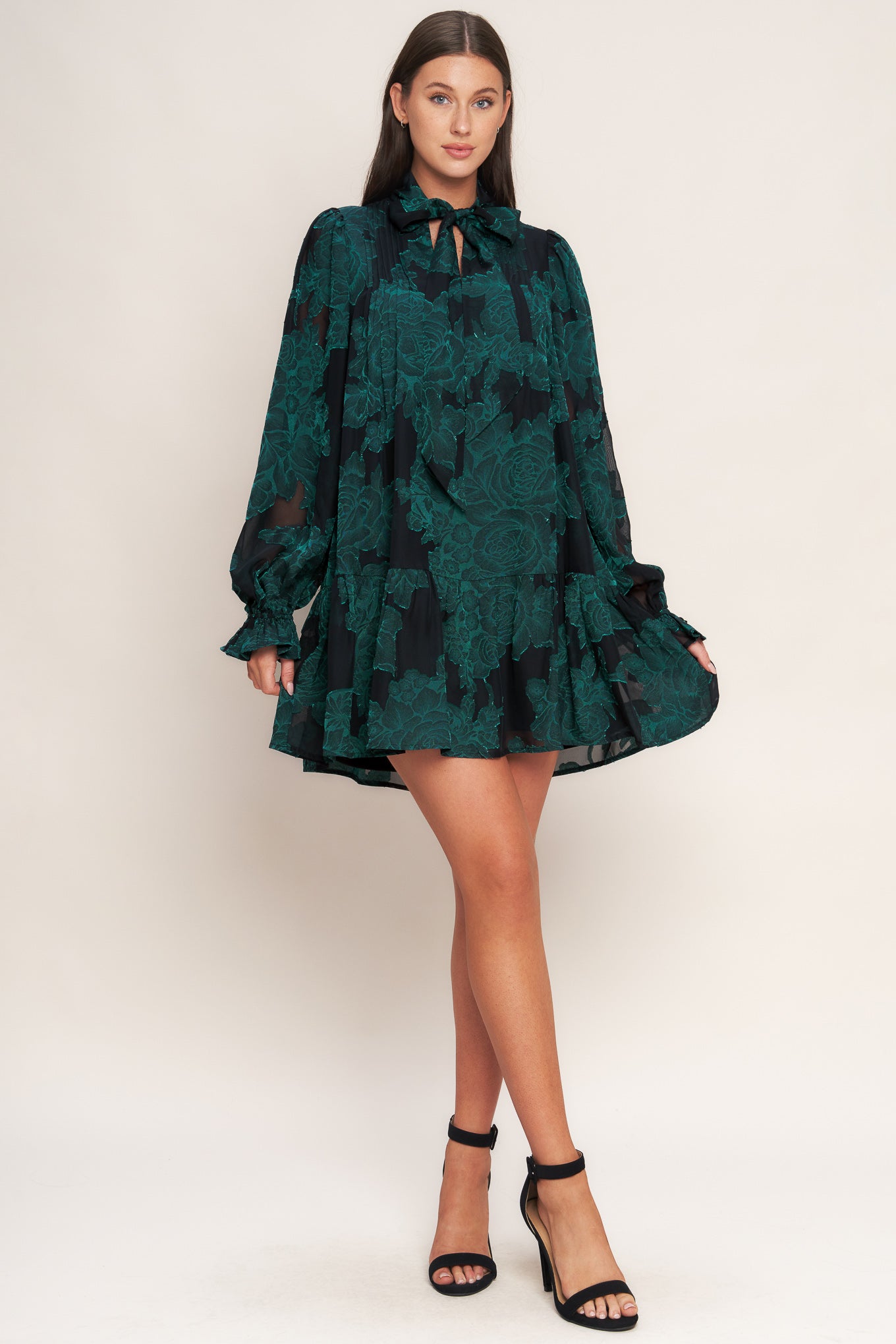 A burnout woven mini dress featuring front tie, long sleeve with ruffled cuff and ruffled hemline