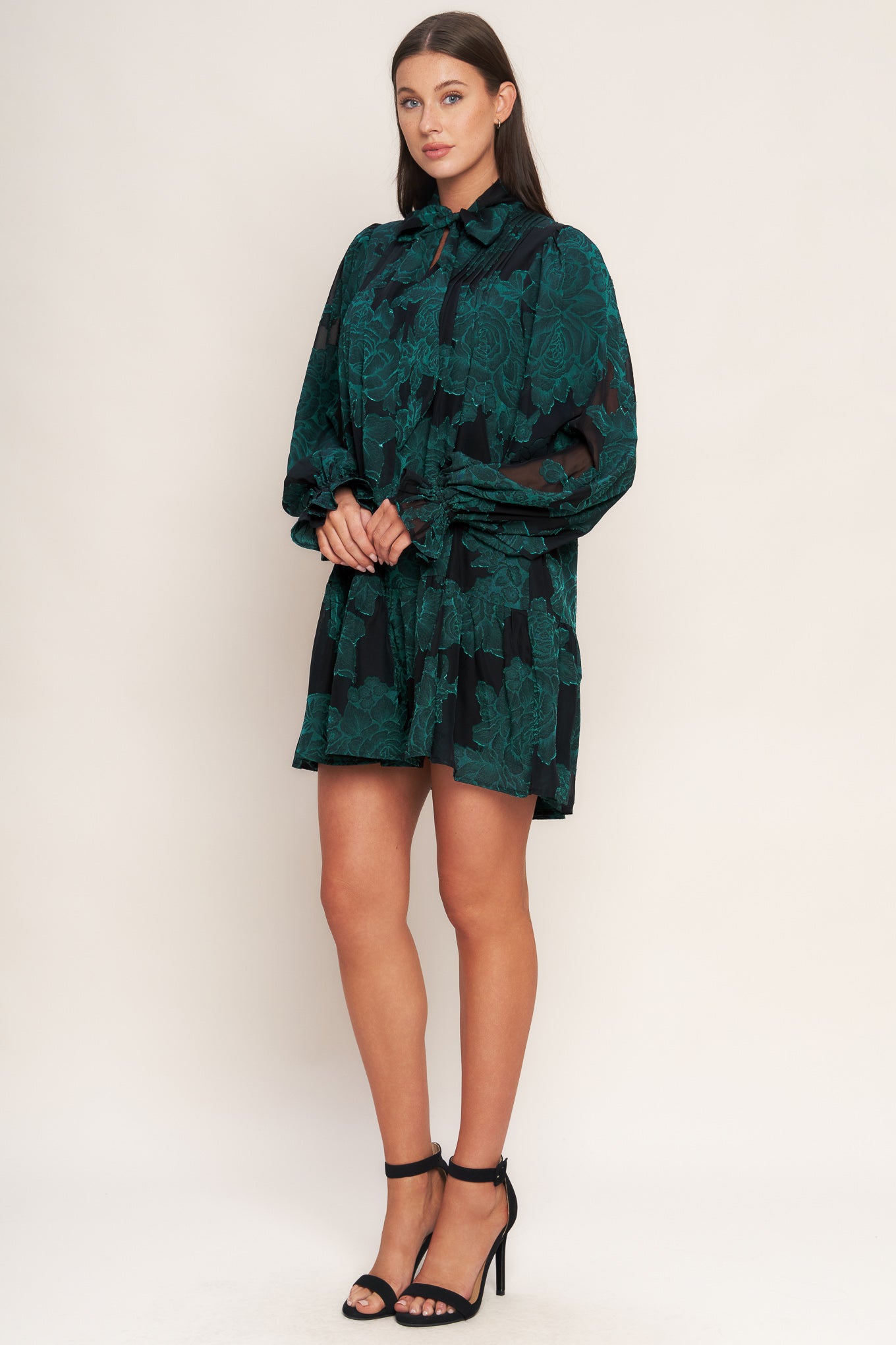 A burnout woven mini dress featuring front tie, long sleeve with ruffled cuff and ruffled hemline