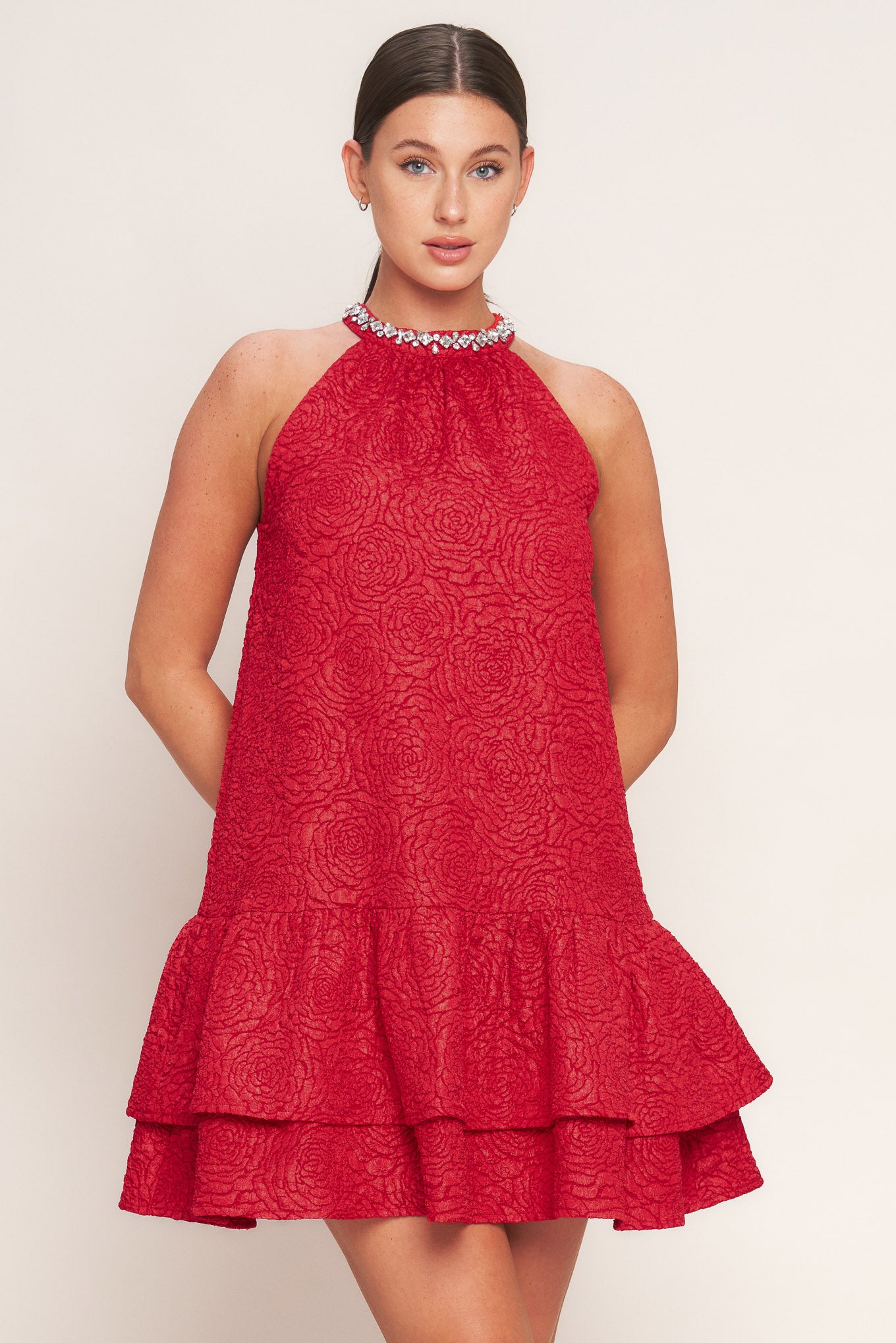 A textured woven mini dress featuring halter neckline with jewel embellishment, double ruffled hem and back neck button closure