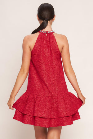 A textured woven mini dress featuring halter neckline with jewel embellishment, double ruffled hem and back neck button closure