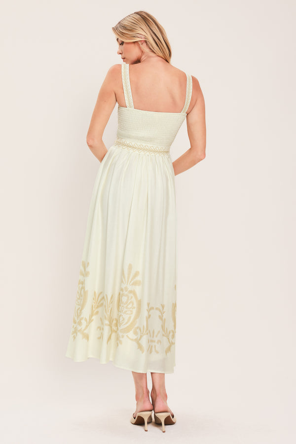 Woman wearing a ivory sleeveless dress with gold embroidery featuring straight neckline, straps, self sash tie with tassel, full skirt and smocked back bodice | Flying Tomato