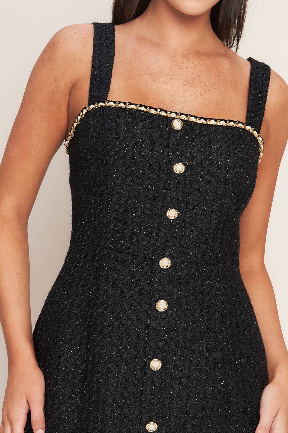 A tweed mini dress featuring trimmed straight neckline, straps, front button down detail and back zipper closure