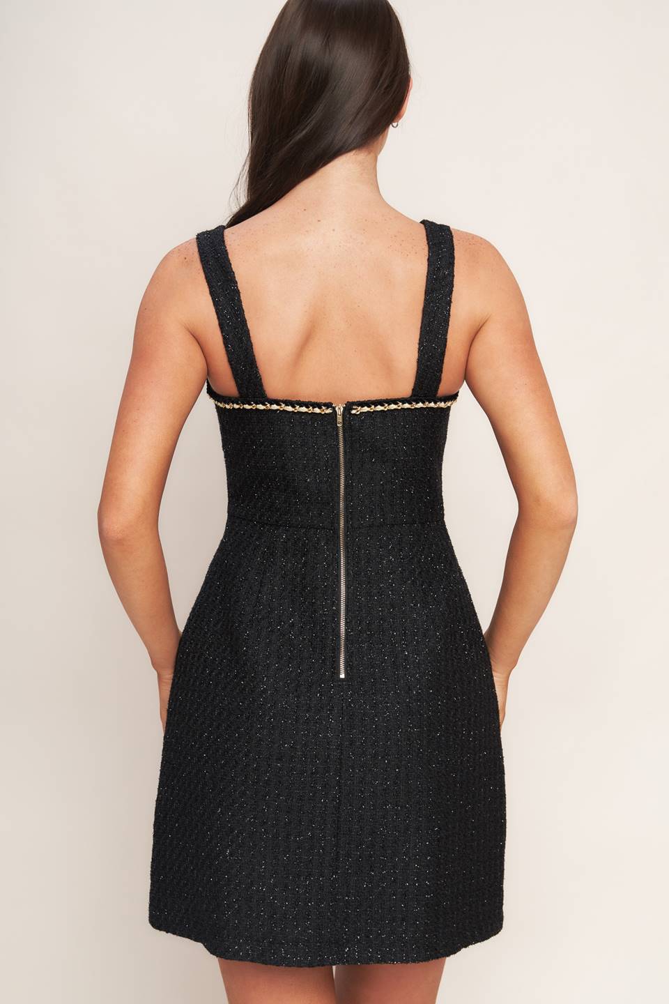 A tweed mini dress featuring trimmed straight neckline, straps, front button down detail and back zipper closure