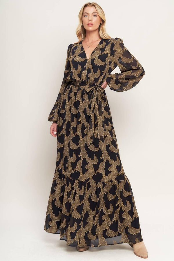 A woven jacquard maxi dress featuring surplice neckline, long sleeve, elasticized waist with self sash and ruffled hemline