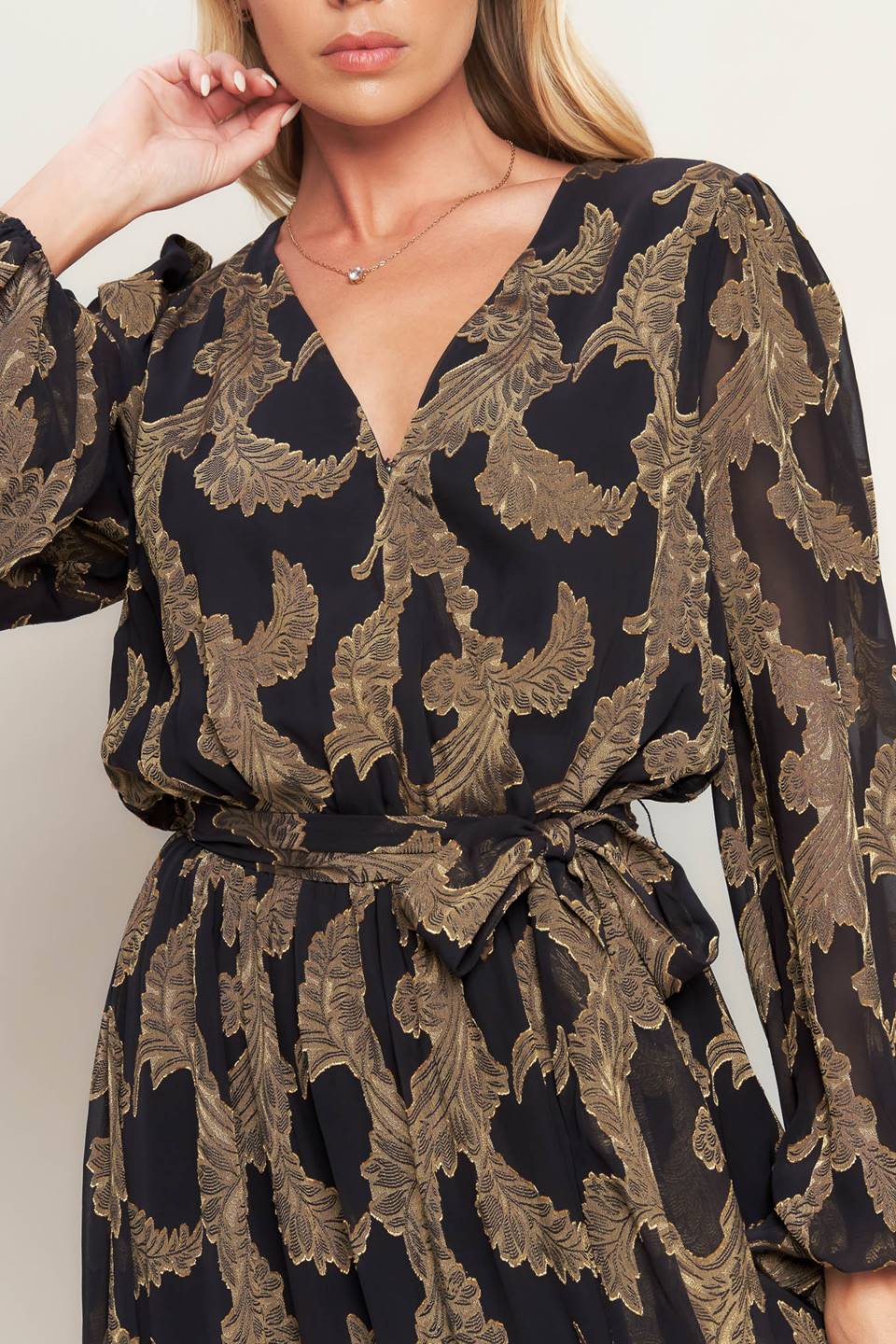 A woven jacquard maxi dress featuring surplice neckline, long sleeve, elasticized waist with self sash and ruffled hemline
