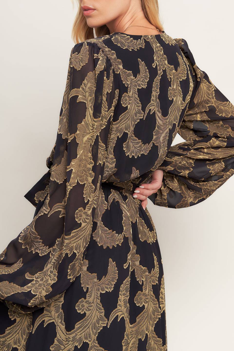 A woven jacquard maxi dress featuring surplice neckline, long sleeve, elasticized waist with self sash and ruffled hemline