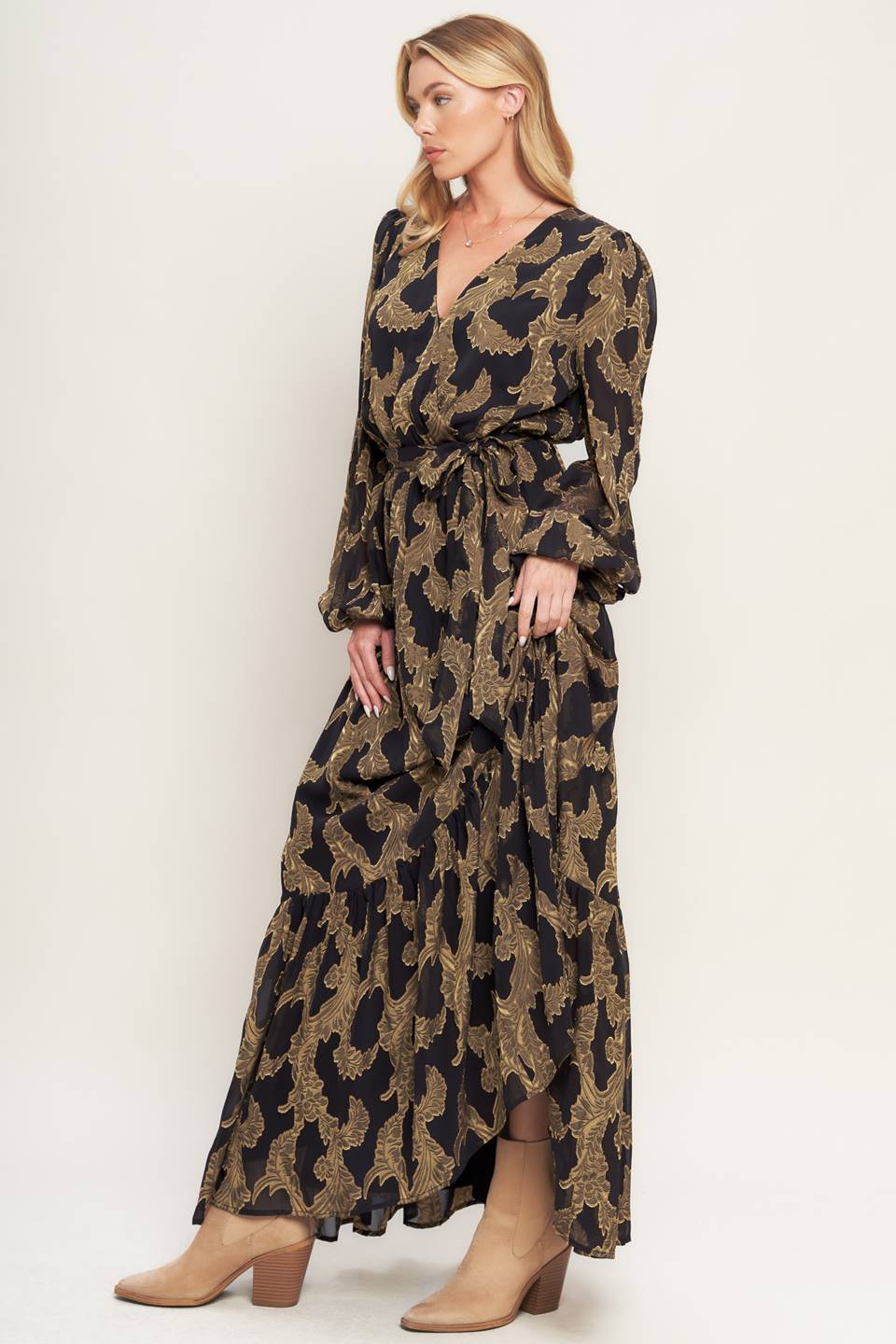 A woven jacquard maxi dress featuring surplice neckline, long sleeve, elasticized waist with self sash and ruffled hemline
