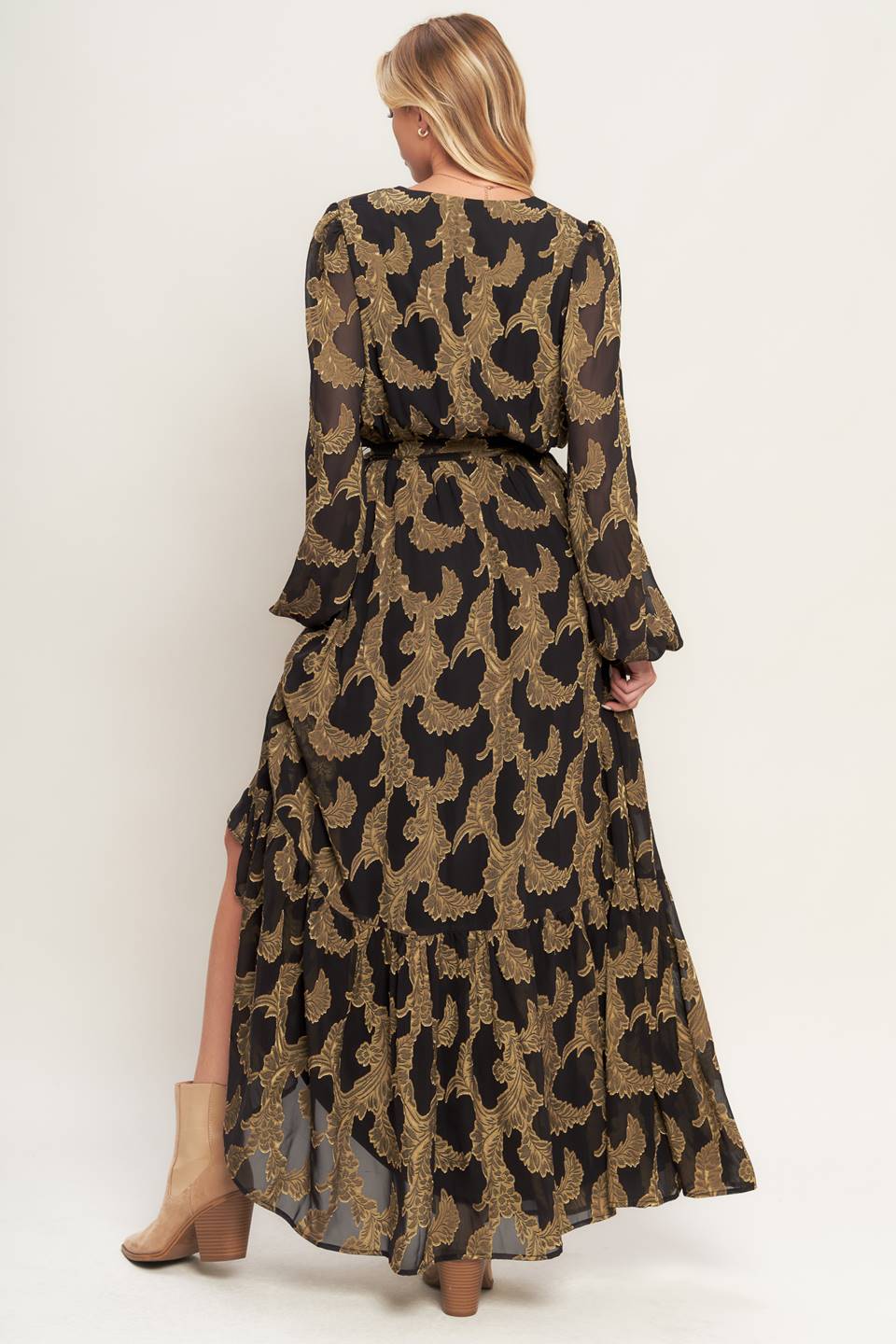 A woven jacquard maxi dress featuring surplice neckline, long sleeve, elasticized waist with self sash and ruffled hemline