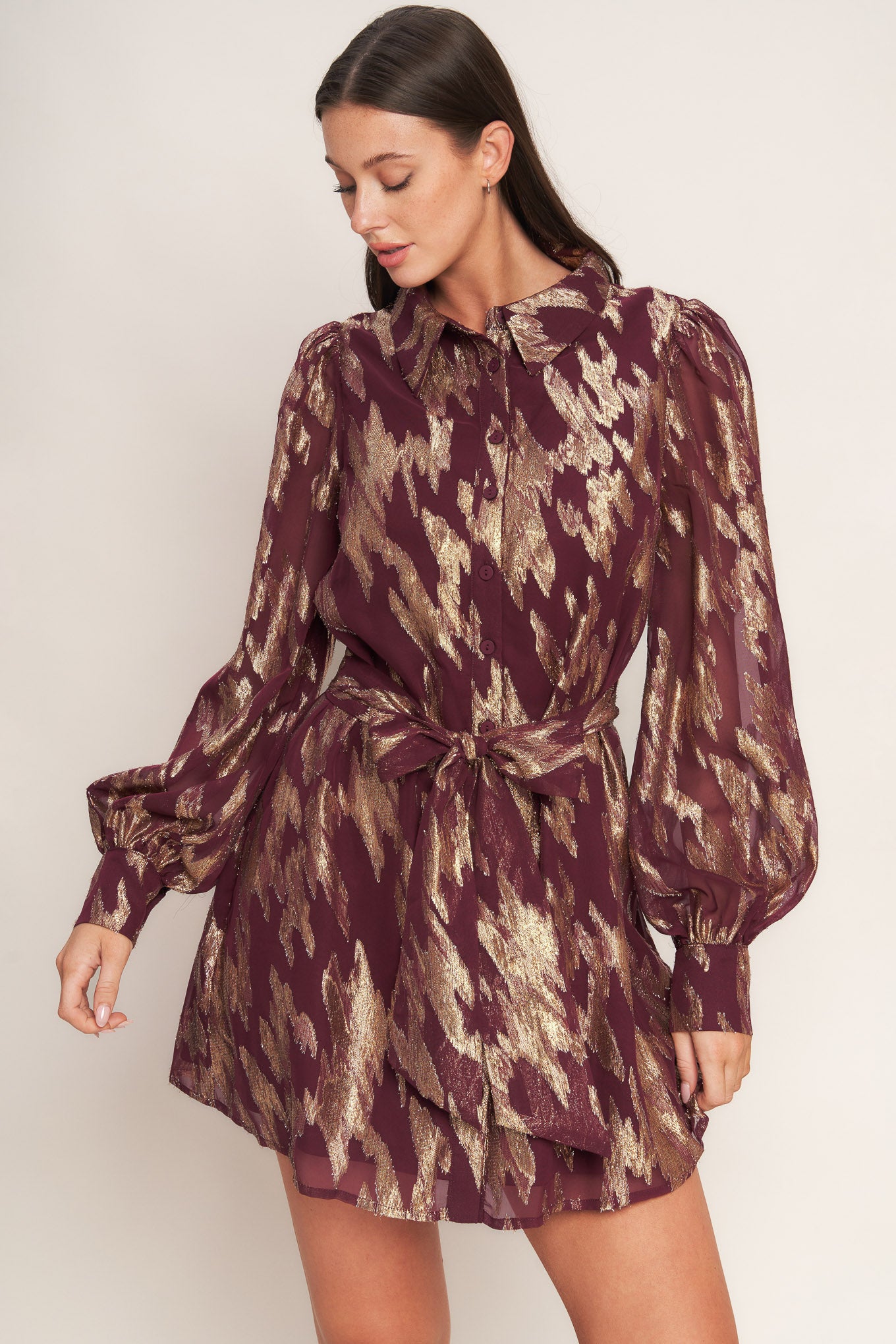 A metallic threaded woven mini dress featuring collar, bow tie, front button down and long sleeve with cuff