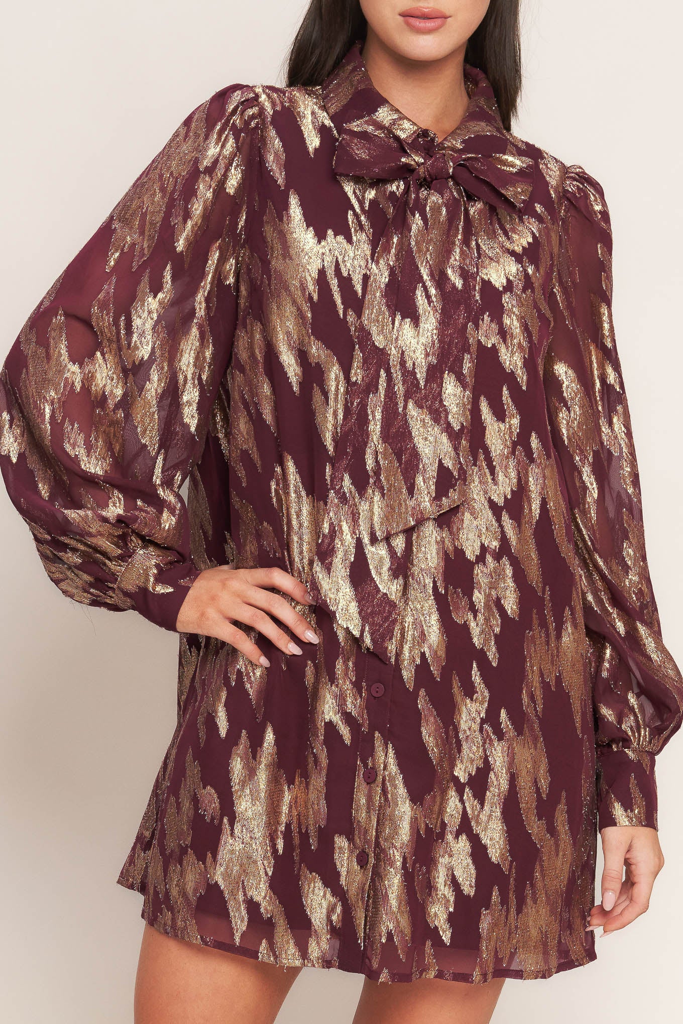 A metallic threaded woven mini dress featuring collar, bow tie, front button down and long sleeve with cuff